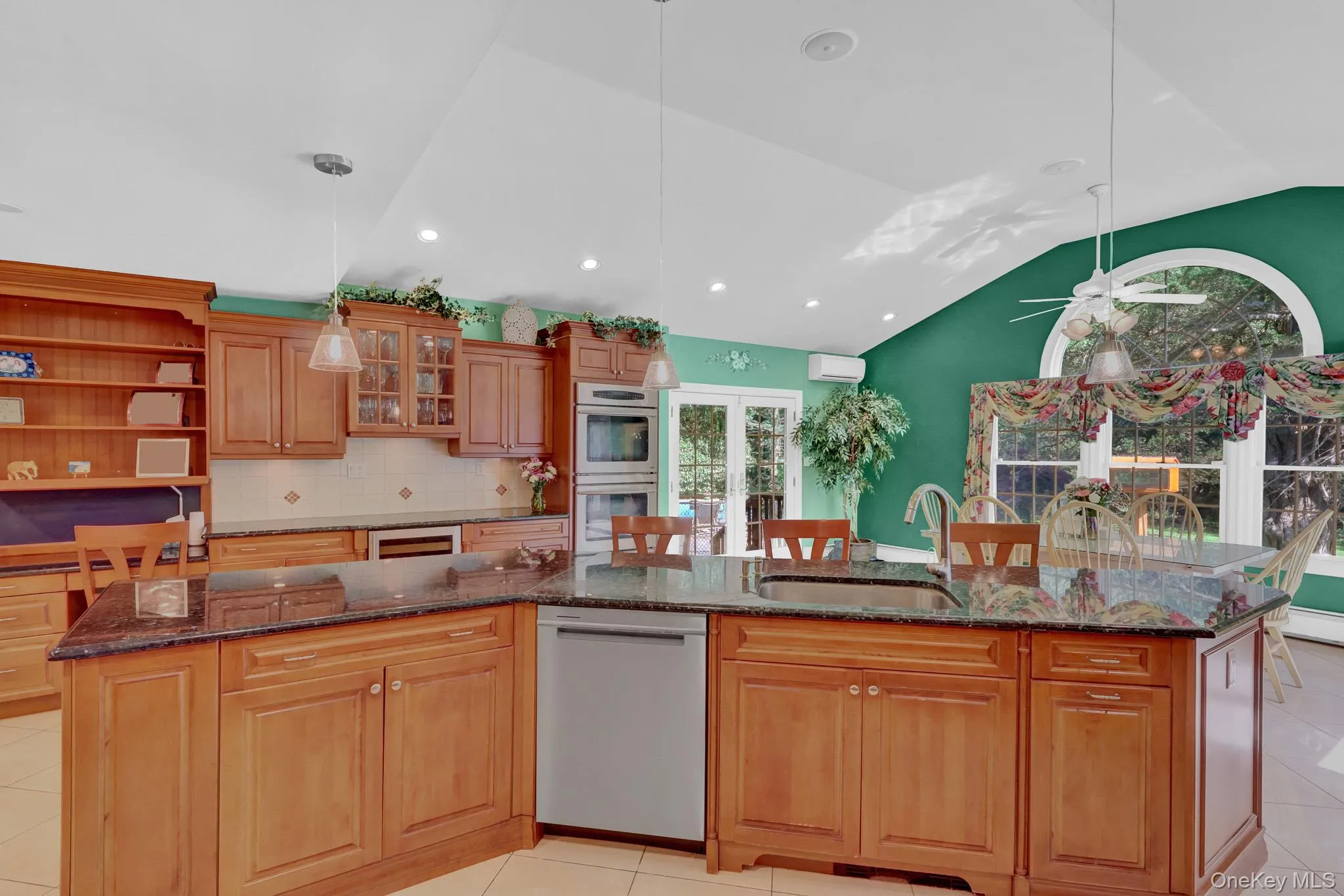 Kitchen featuring a multi-level island with integrated sink, wood-finish cabinetry, built-in double oven, and recessed lighting Kitchen featuring a multi-level island with integrated sink, wood-finish cabinetry, built-in double oven, and recessed lighting