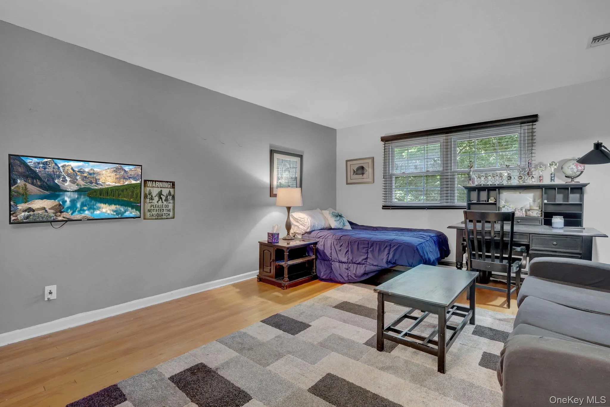 3rd primary upstairs Spacious room featuring wood-finish flooring, a large window with blinds, and a built-in desk with shelving 3rd primary upstairs Spacious room featuring wood-finish flooring, a large window with blinds, and a built-in desk with shelving