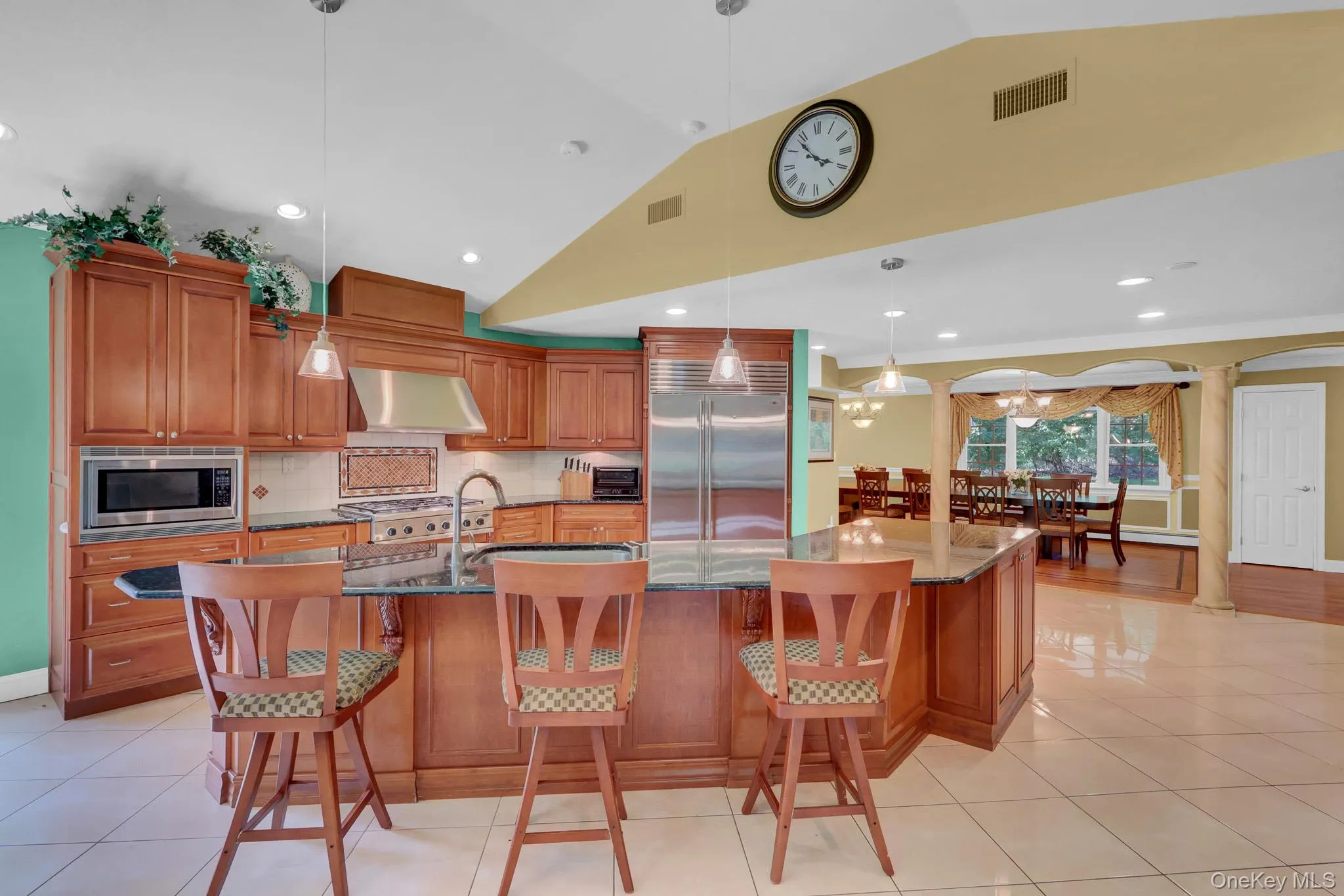 Kitchen featuring wood cabinetry, stainless steel appliances, a center island with bar seating, and tile flooring Kitchen featuring wood cabinetry, stainless steel appliances, a center island with bar seating, and tile flooring