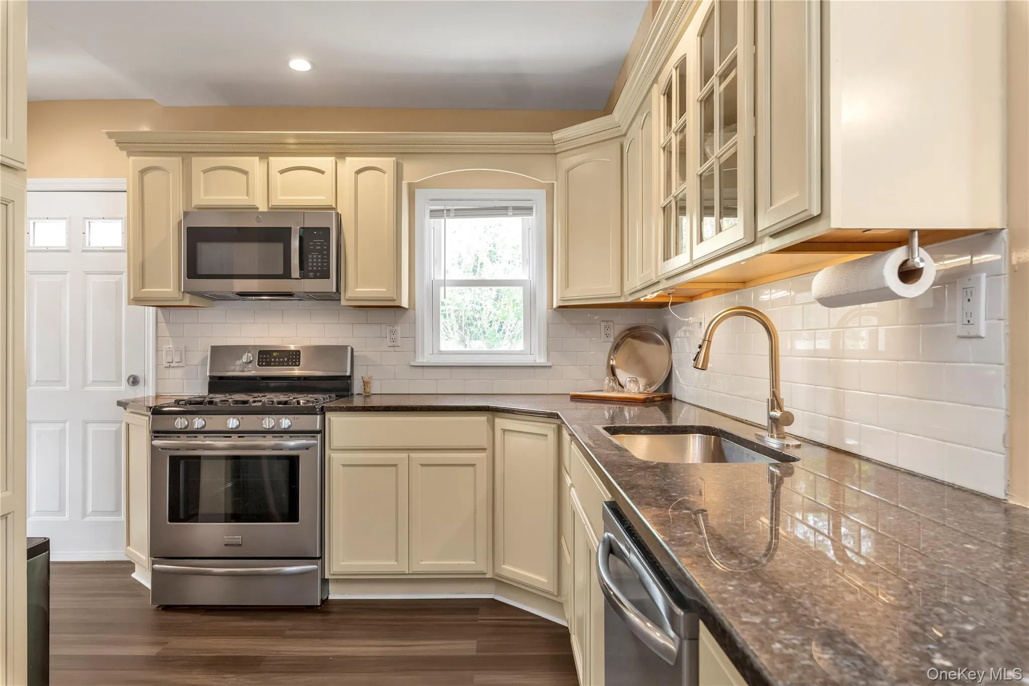 Kitchen featuring stainless steel appliances,granite countertops,and tile backsplash Kitchen featuring stainless steel appliances,granite countertops,and tile backsplash