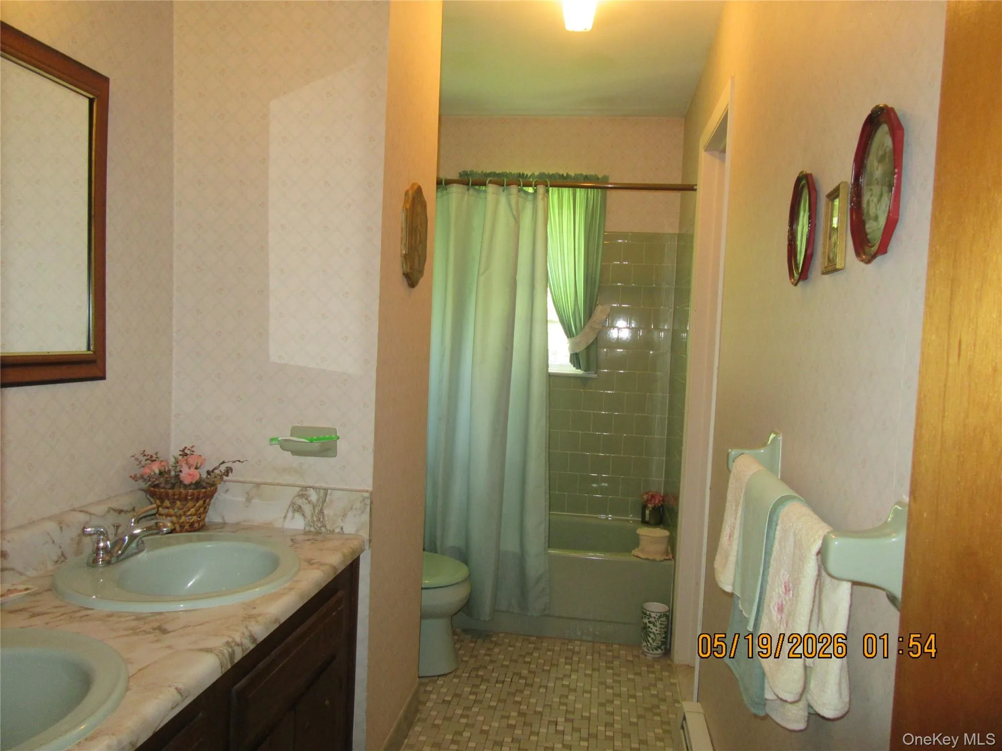 Bathroom featuring dual basin vanity with a marble-finish countertop, wood-finish cabinetry, and a full-size mirror Bathroom featuring dual basin vanity with a marble-finish countertop, wood-finish cabinetry, and a full-size mirror