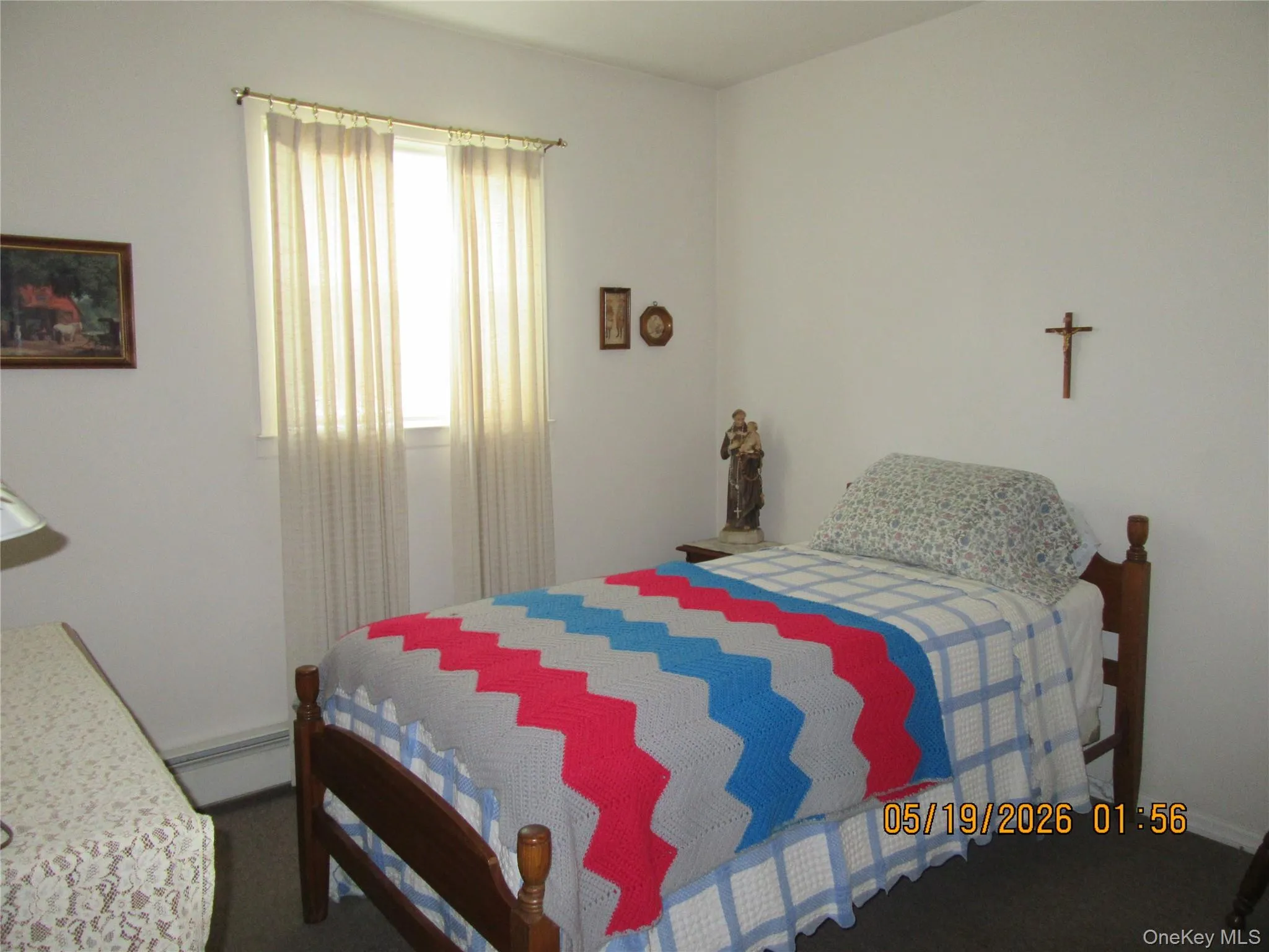 Room featuring a window with sheer curtains, a dark wood-finish bed frame, and light-colored walls Room featuring a window with sheer curtains, a dark wood-finish bed frame, and light-colored walls