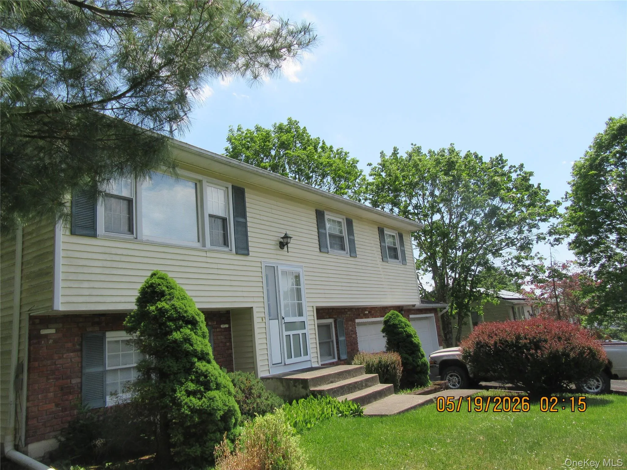 Split-level residence featuring yellow siding and a brick lower level Split-level residence featuring yellow siding and a brick lower level