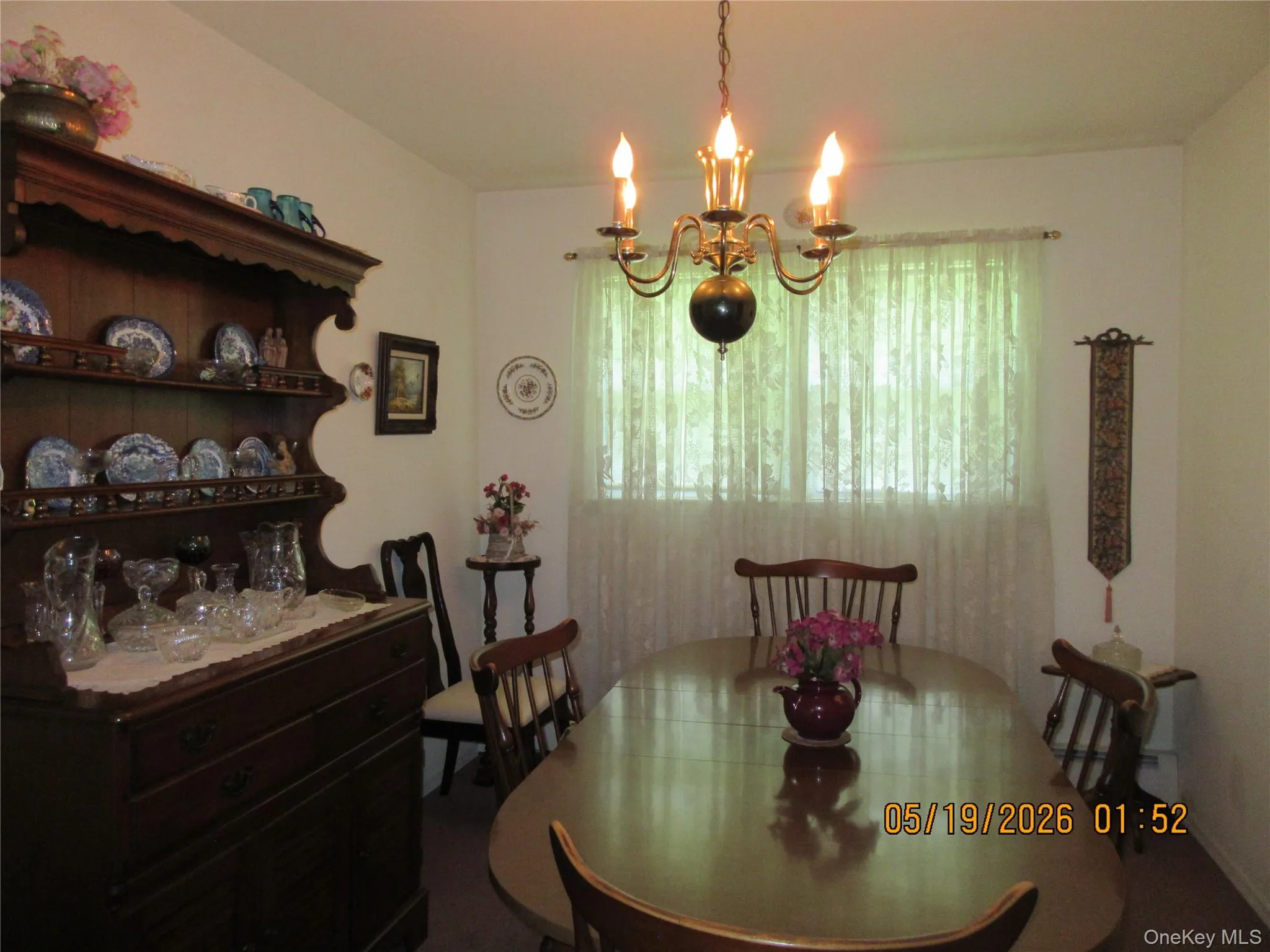 Dining area featuring a classic chandelier, a large window, light-colored walls, and carpeting Dining area featuring a classic chandelier, a large window, light-colored walls, and carpeting