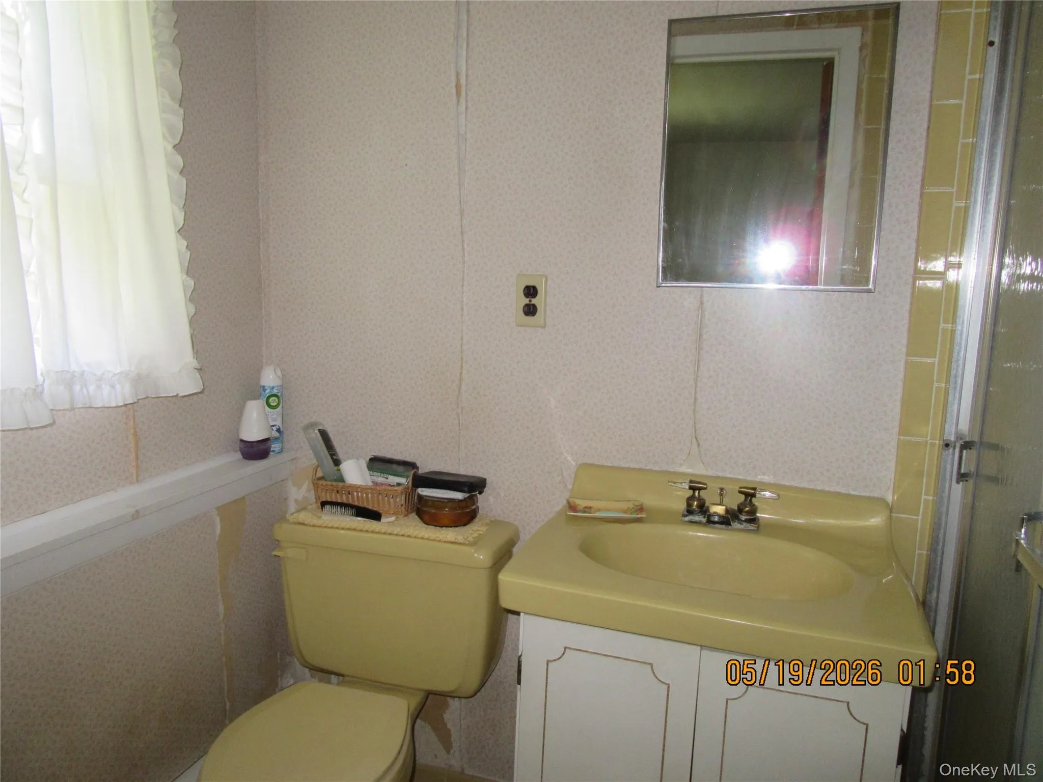 Bathroom featuring a pale yellow vanity and toilet, a mirrored medicine cabinet, and a shower enclosure with yellow tiled walls Bathroom featuring a pale yellow vanity and toilet, a mirrored medicine cabinet, and a shower enclosure with yellow tiled walls