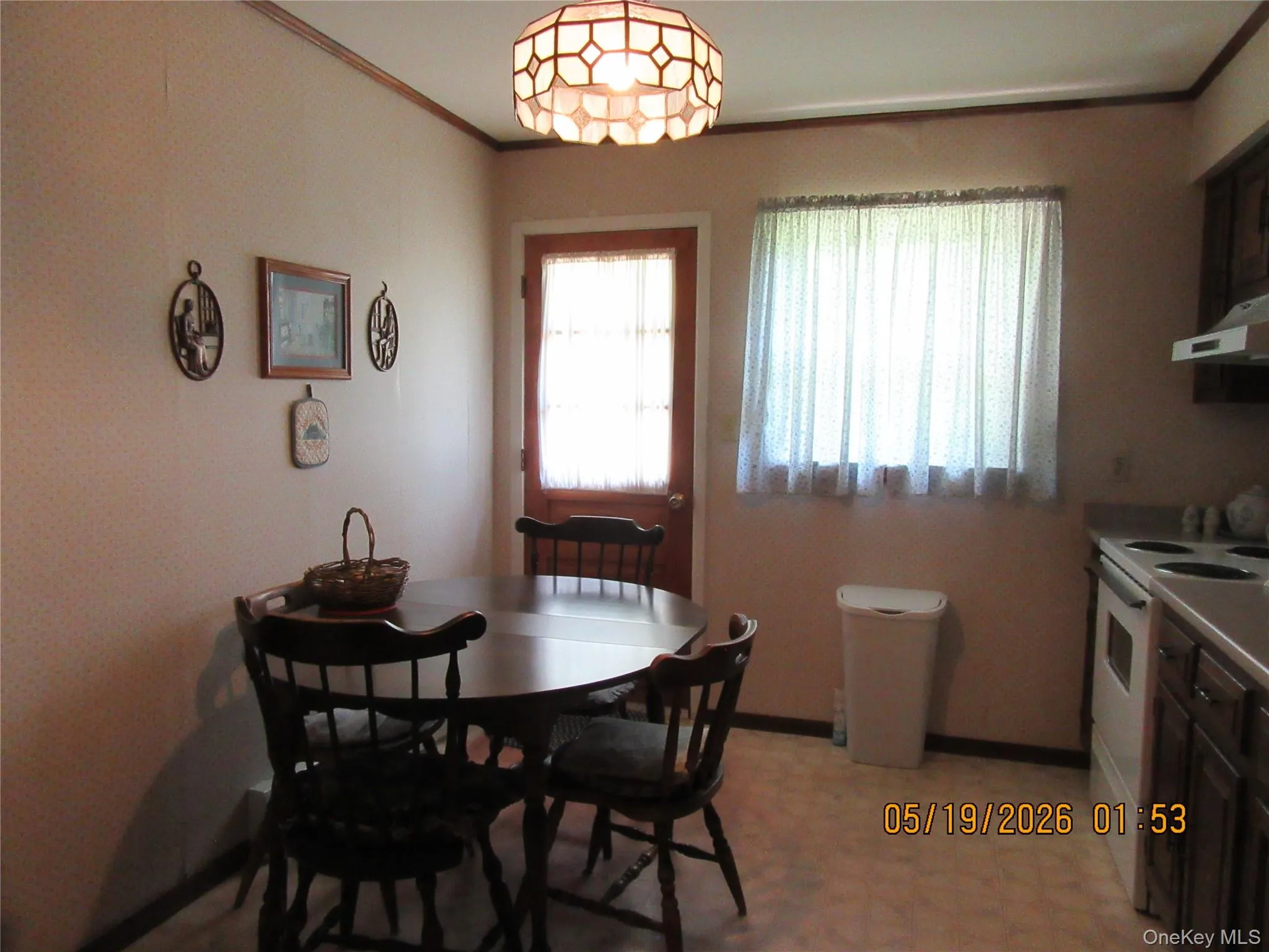 Kitchen area featuring a window with white curtains, a patterned ceiling light fixture, a paneled door, and wood-finish trim Kitchen area featuring a window with white curtains, a patterned ceiling light fixture, a paneled door, and wood-finish trim