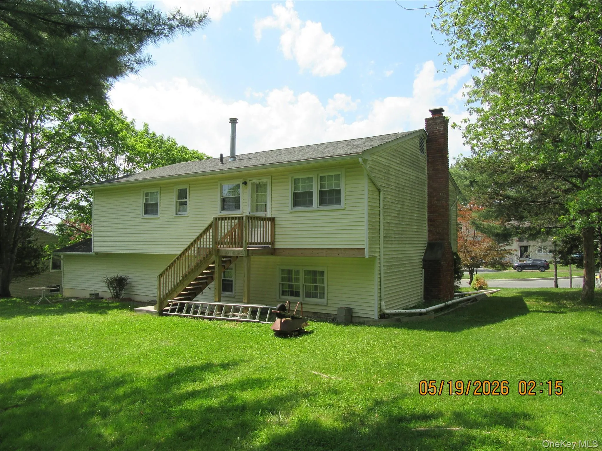 Rear exterior featuring a wood deck with stairs, a brick chimney, and a full-light rear door Rear exterior featuring a wood deck with stairs, a brick chimney, and a full-light rear door