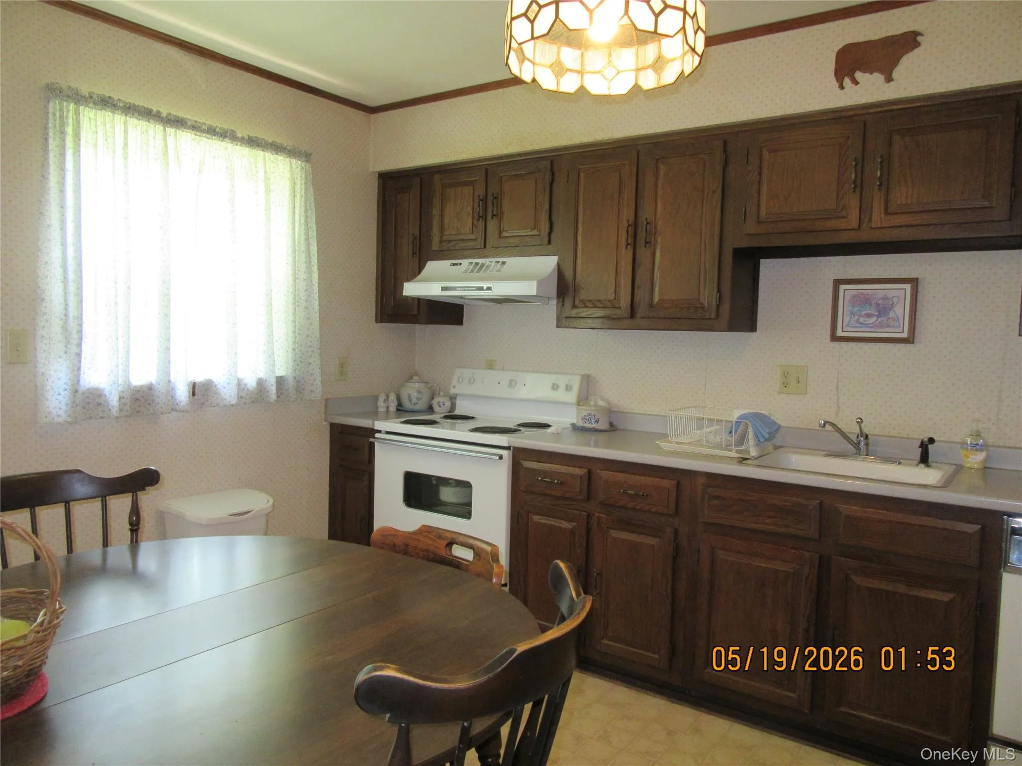 Kitchen featuring wood-finish cabinetry, a white electric range with range hood, and a built-in sink Kitchen featuring wood-finish cabinetry, a white electric range with range hood, and a built-in sink