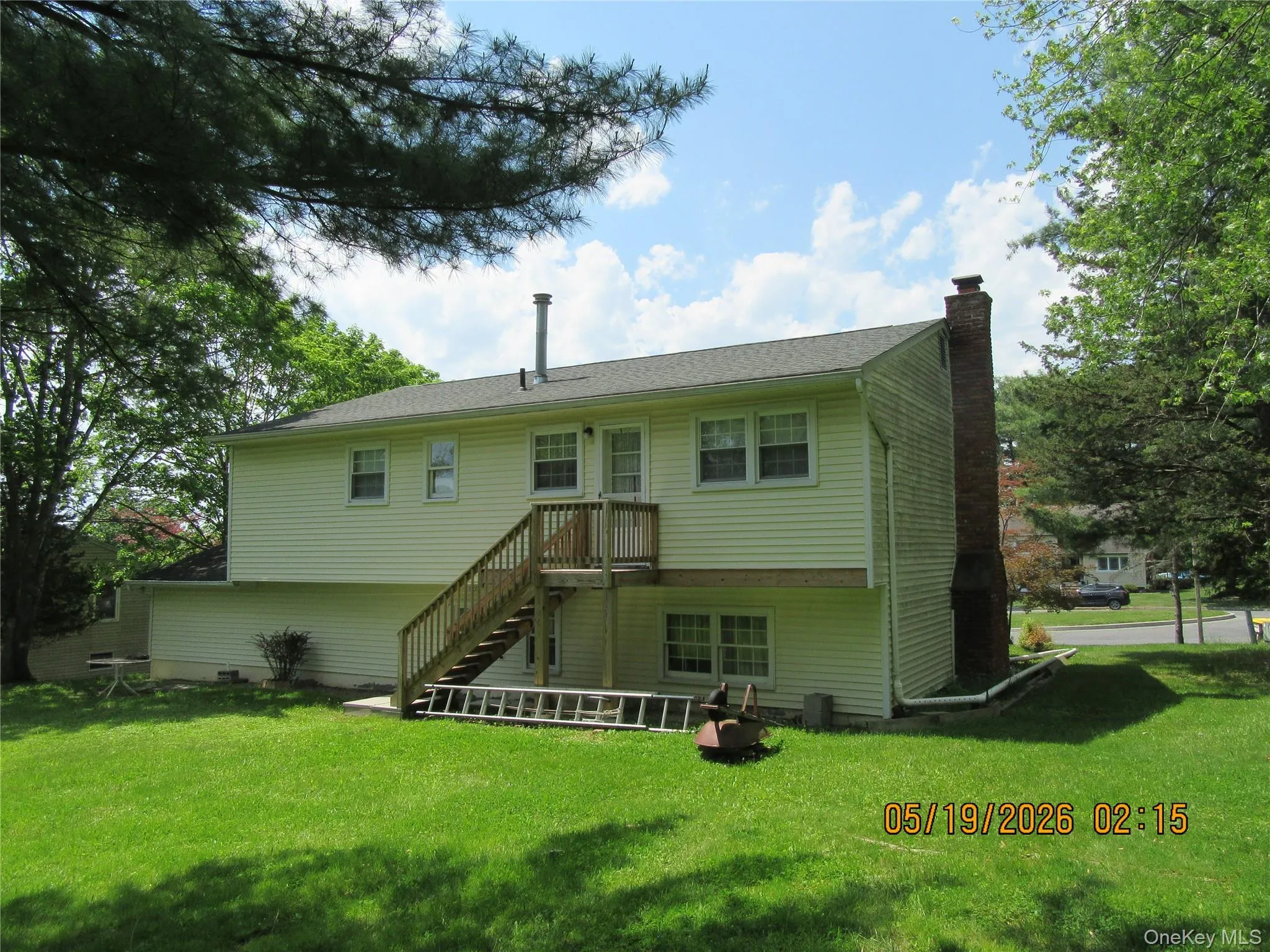 Rear exterior featuring siding, a second-story wood deck with stairs, multiple windows, and an exposed brick chimney Rear exterior featuring siding, a second-story wood deck with stairs, multiple windows, and an exposed brick chimney