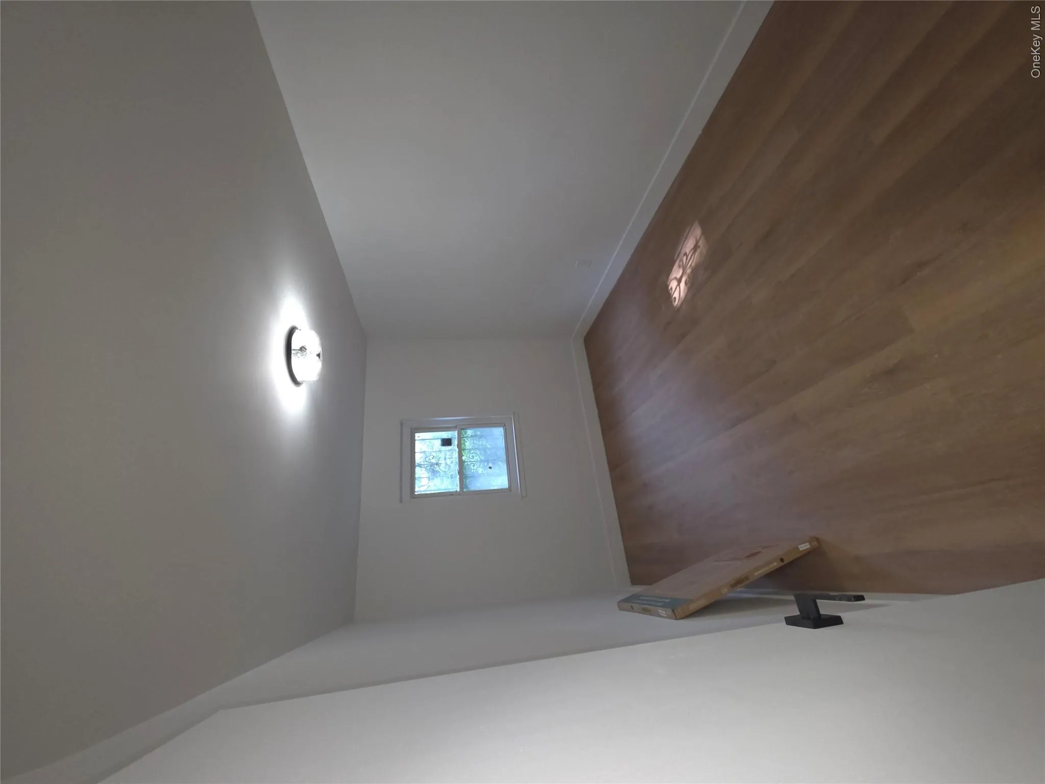 Bright interior space featuring wood-finish flooring, white walls, and a ceiling-mounted light fixture Bright interior space featuring wood-finish flooring, white walls, and a ceiling-mounted light fixture