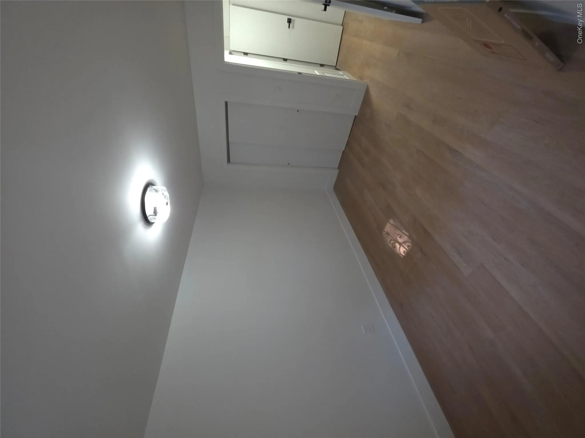 Bright interior space featuring light wood-finish flooring, white baseboards, and a modern ceiling light fixture Bright interior space featuring light wood-finish flooring, white baseboards, and a modern ceiling light fixture