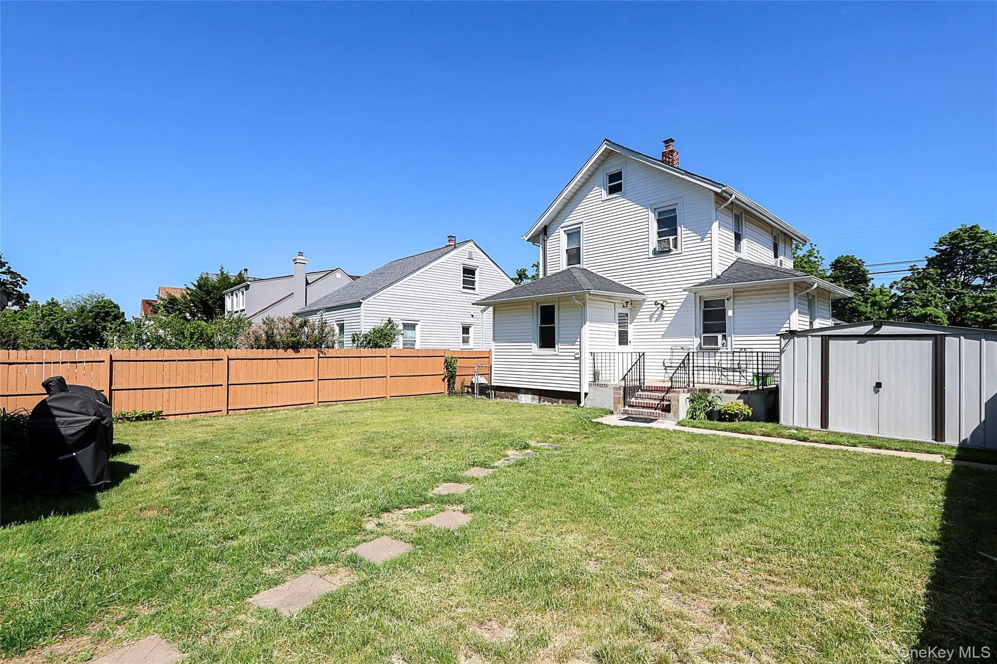 Expansive backyard featuring a wood fence, concrete patio, and a metal storage shed Expansive backyard featuring a wood fence, concrete patio, and a metal storage shed