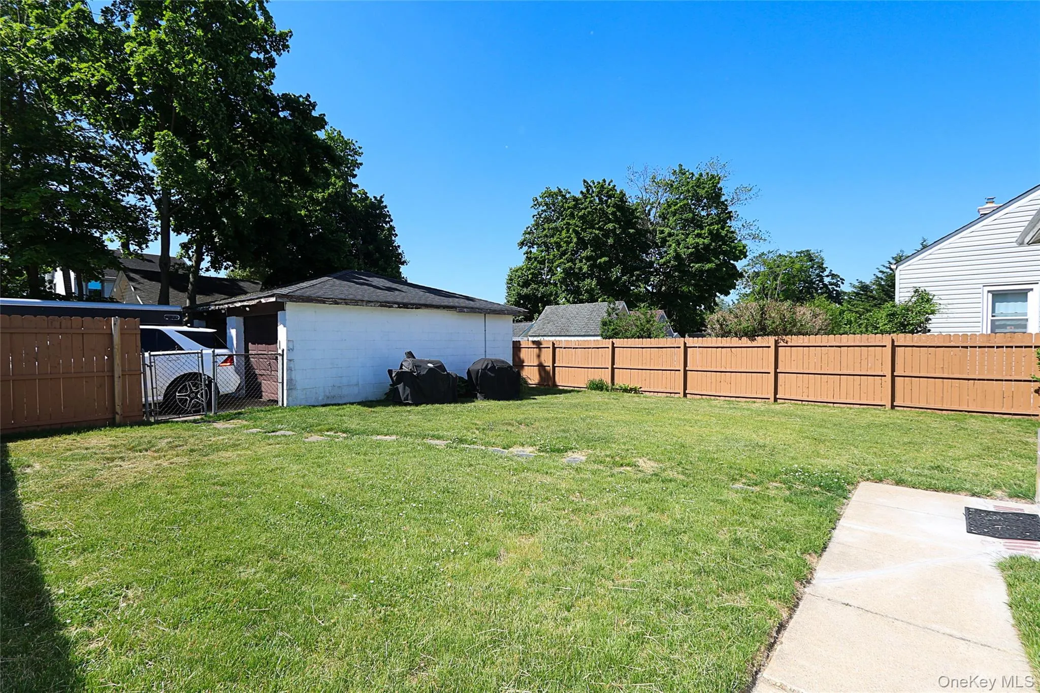Expansive backyard featuring a manicured lawn, a detached garage, and a brown privacy fence Expansive backyard featuring a manicured lawn, a detached garage, and a brown privacy fence