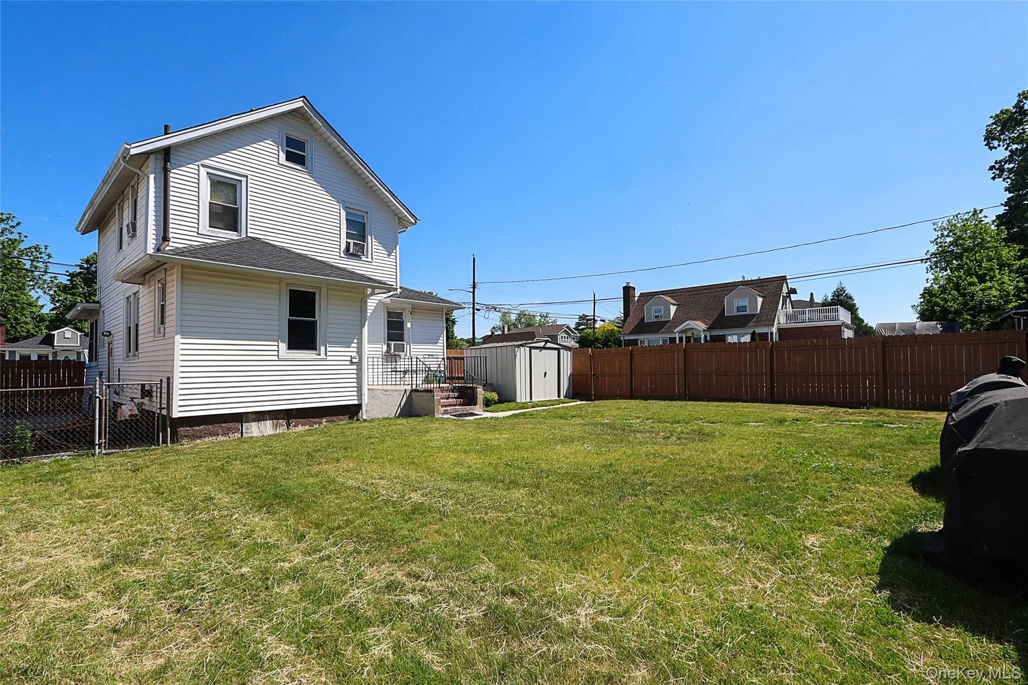 Expansive backyard featuring a manicured lawn, full privacy fencing, and a utility shed Expansive backyard featuring a manicured lawn, full privacy fencing, and a utility shed