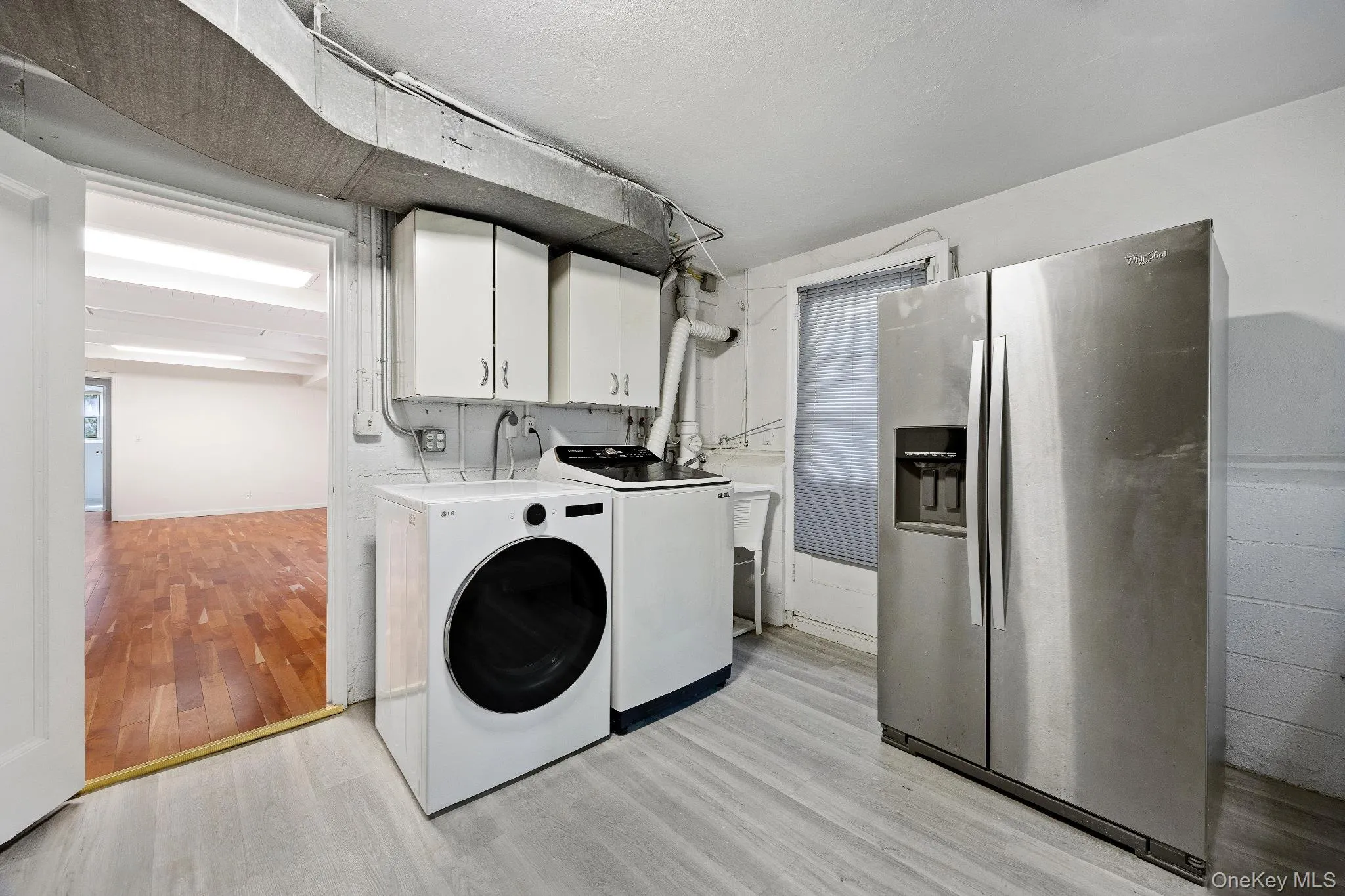 Laundry area with light wood-style flooring, cabinet space, and washer and clothes dryer Laundry area with light wood-style flooring, cabinet space, and washer and clothes dryer