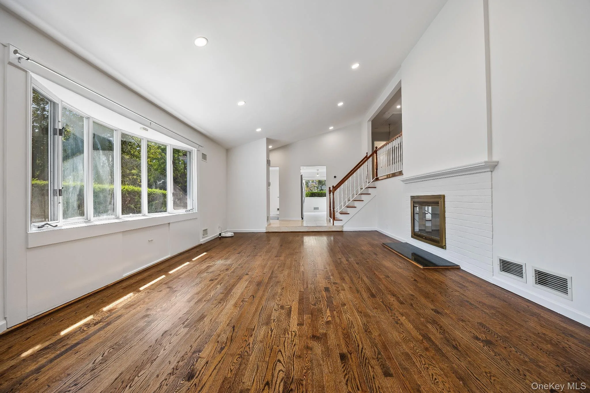 Unfurnished living room featuring dark wood-style floors, recessed lighting, stairs, and high vaulted ceiling Unfurnished living room featuring dark wood-style floors, recessed lighting, stairs, and high vaulted ceiling