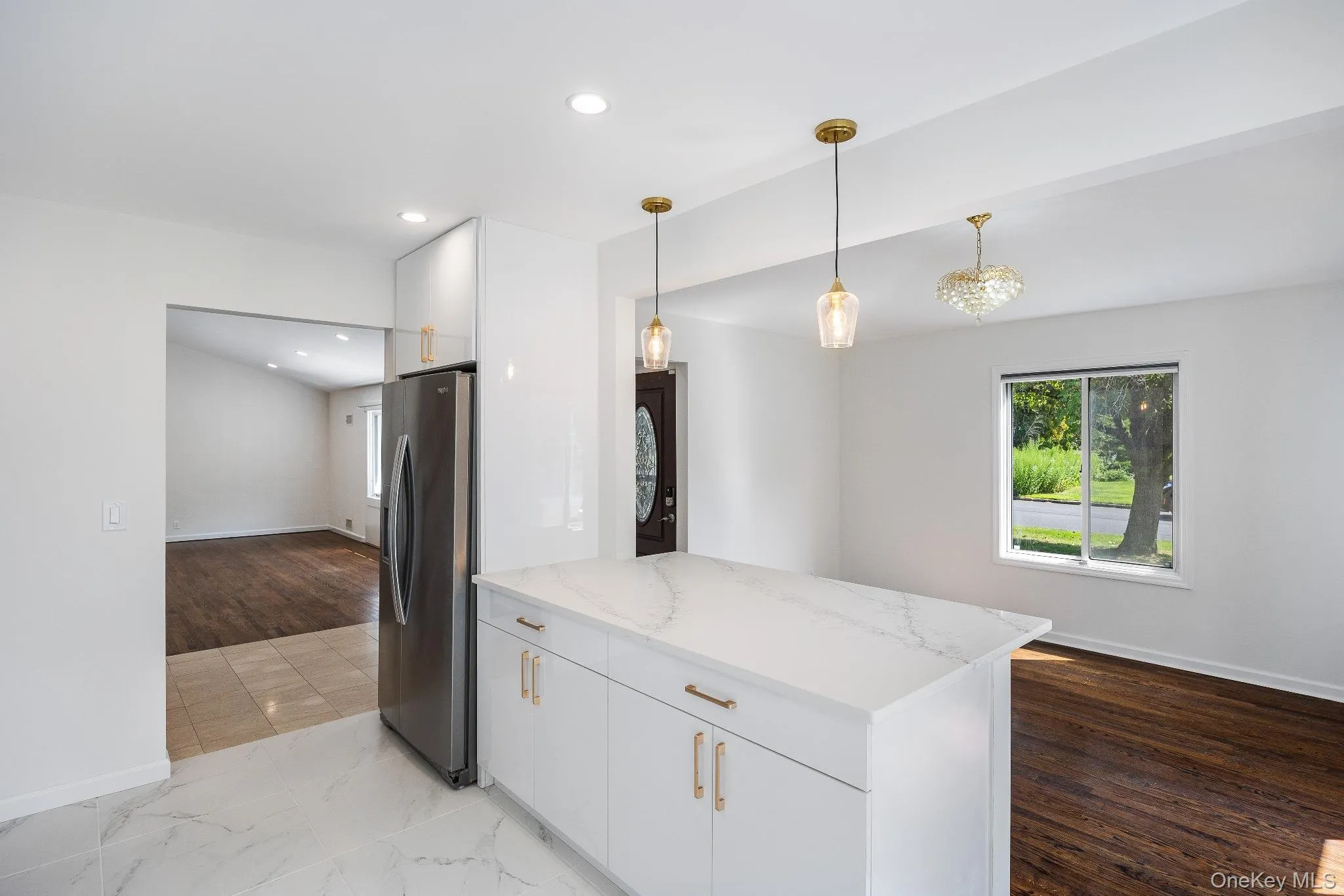 Kitchen featuring white cabinets, hanging light fixtures, stainless steel fridge with ice dispenser, light stone counters, and recessed lighting Kitchen featuring white cabinets, hanging light fixtures, stainless steel fridge with ice dispenser, light stone counters, and recessed lighting
