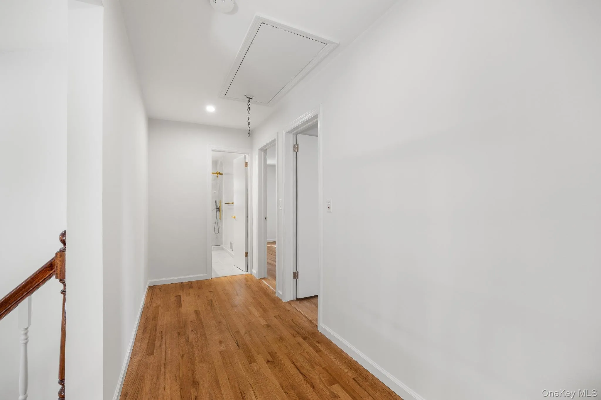 Corridor with attic access, light wood-style floors, recessed lighting, and an upstairs landing Corridor with attic access, light wood-style floors, recessed lighting, and an upstairs landing