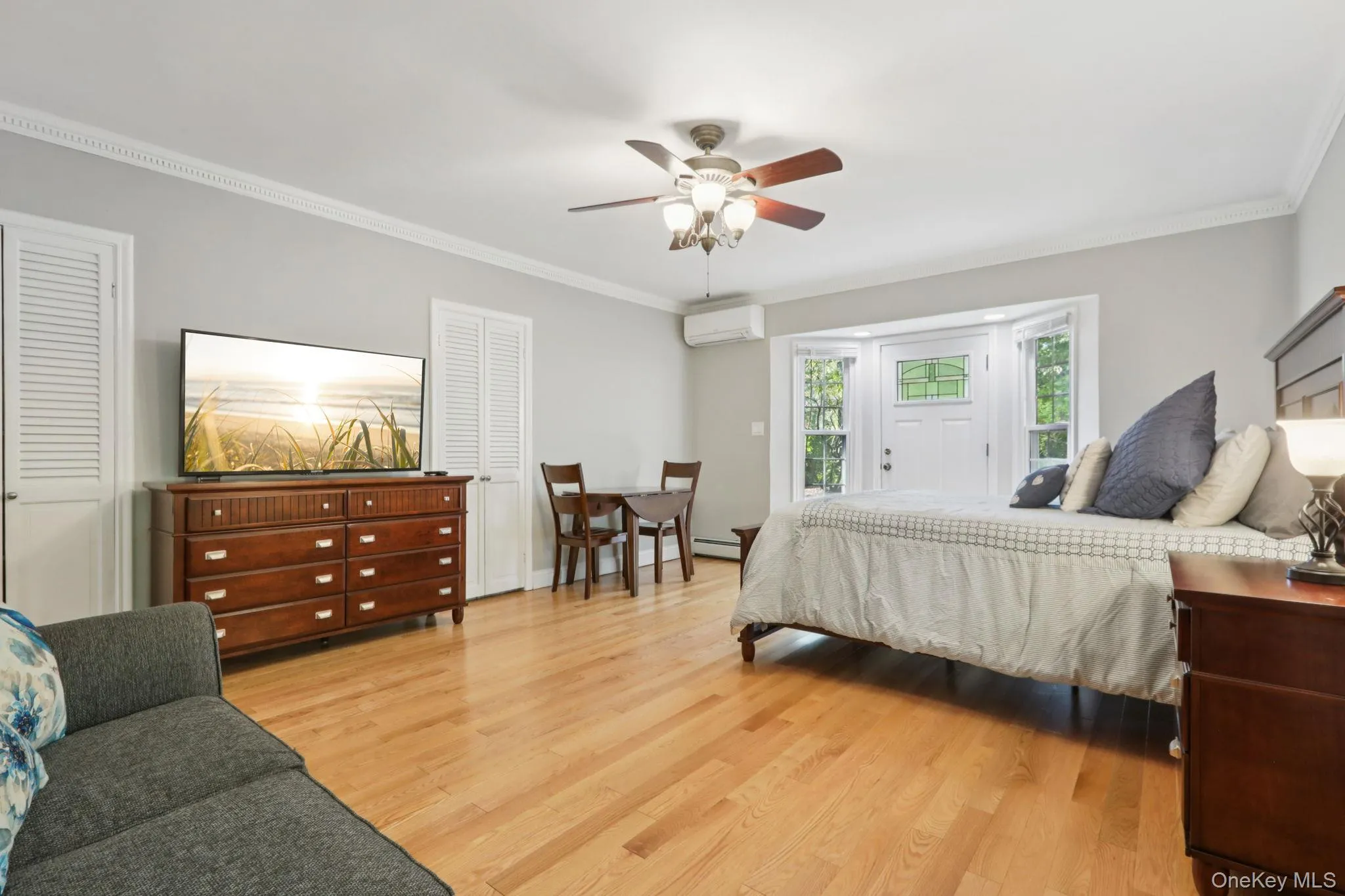 Primary bedroom with wood floors, additional sitting area, closets and private entrance leading to stone patio Primary bedroom with wood floors, additional sitting area, closets and private entrance leading to stone patio