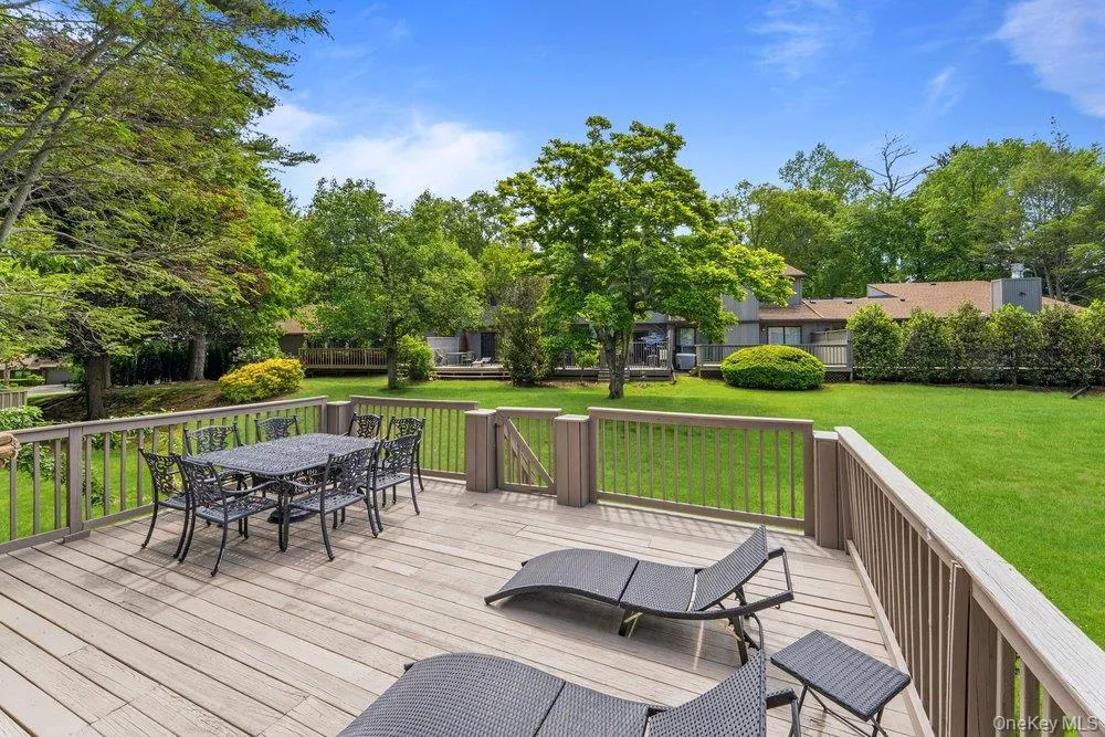 Expansive wood-finish deck with perimeter railing and a gated entry to the yard Expansive wood-finish deck with perimeter railing and a gated entry to the yard