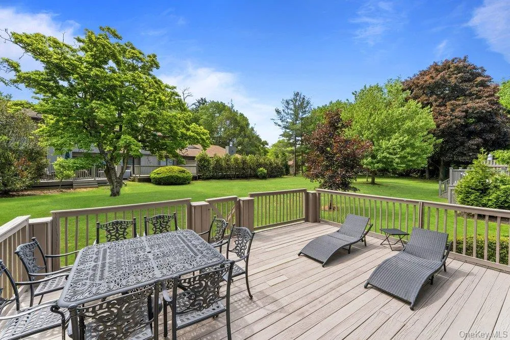 Spacious outdoor deck with wood-finish flooring and a wood railing overlooking an expansive manicured lawn Spacious outdoor deck with wood-finish flooring and a wood railing overlooking an expansive manicured lawn