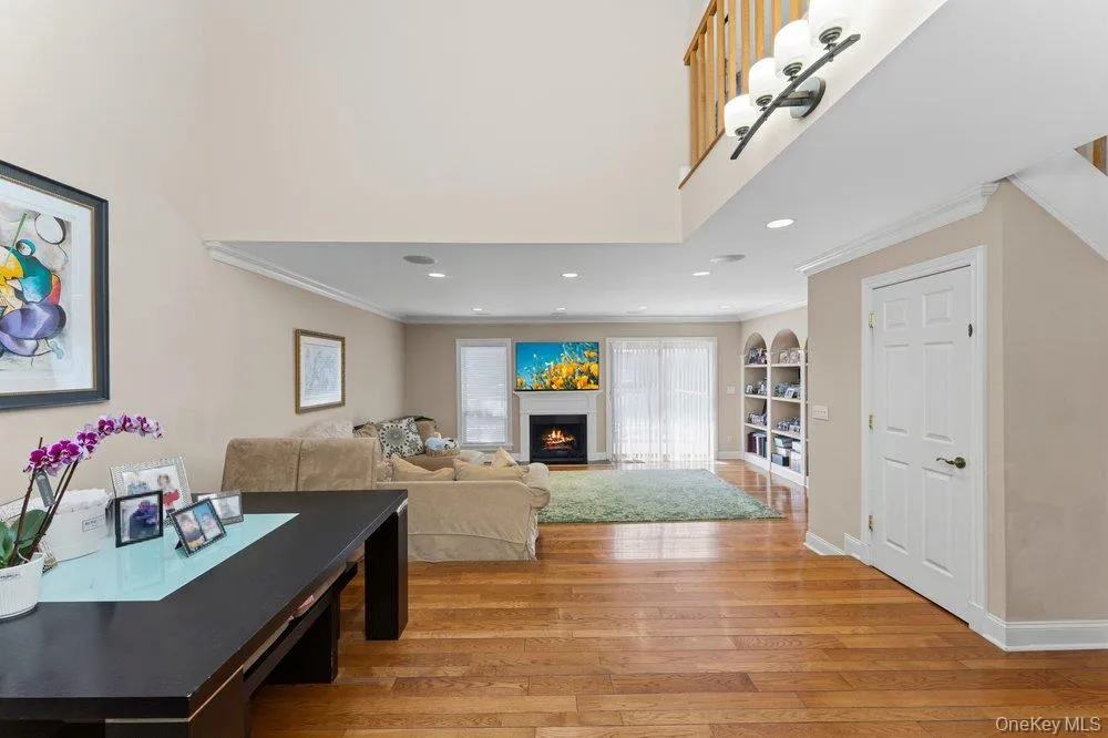 Open-concept living space featuring wood-finish flooring, a fireplace, arched built-in shelving, a sliding glass door, and recessed lighting Open-concept living space featuring wood-finish flooring, a fireplace, arched built-in shelving, a sliding glass door, and recessed lighting