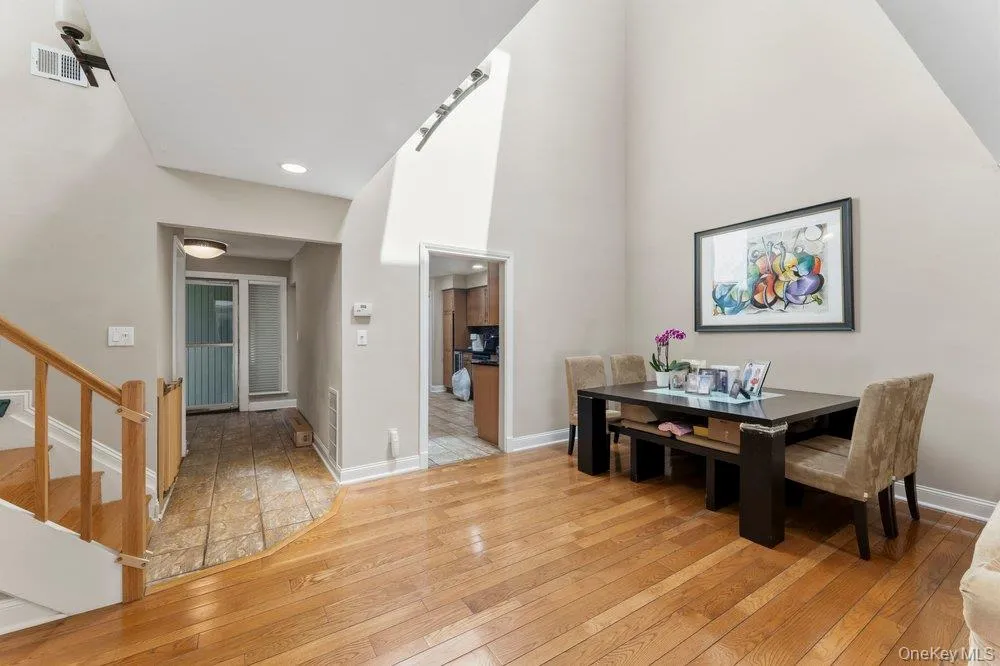 Hardwood flooring extending through the primary living area, complemented by a soaring vaulted ceiling Hardwood flooring extending through the primary living area, complemented by a soaring vaulted ceiling