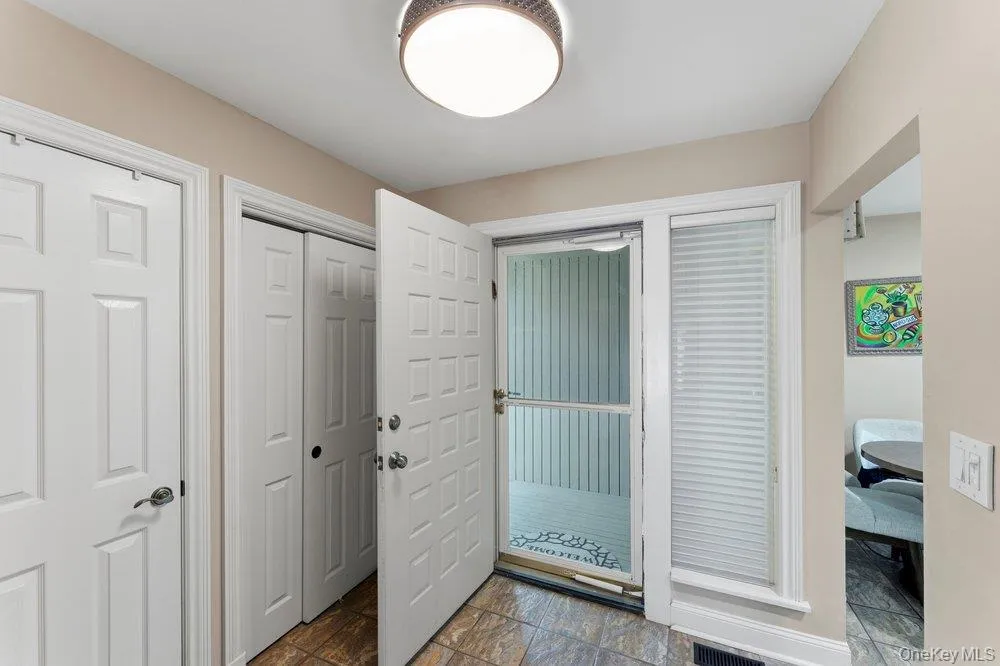 Entryway featuring tiled flooring, a flush-mount ceiling light, white paneled doors, and a front entry door with an adjacent window Entryway featuring tiled flooring, a flush-mount ceiling light, white paneled doors, and a front entry door with an adjacent window