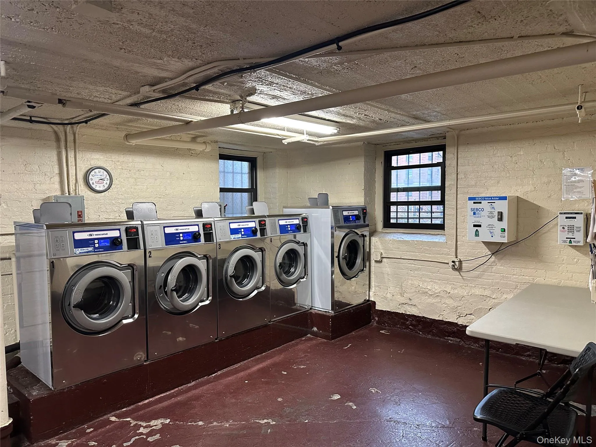Shared laundry area featuring brick wall and washing machine and clothes dryer Shared laundry area featuring brick wall and washing machine and clothes dryer
