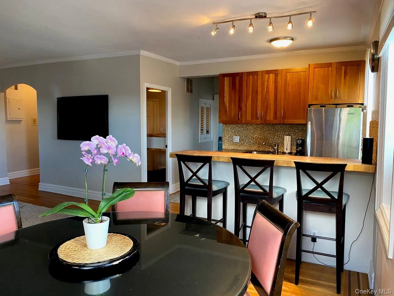Kitchen with light wood-style flooring, arched walkways, freestanding refrigerator, brown cabinets, and wooden counters Kitchen with light wood-style flooring, arched walkways, freestanding refrigerator, brown cabinets, and wooden counters