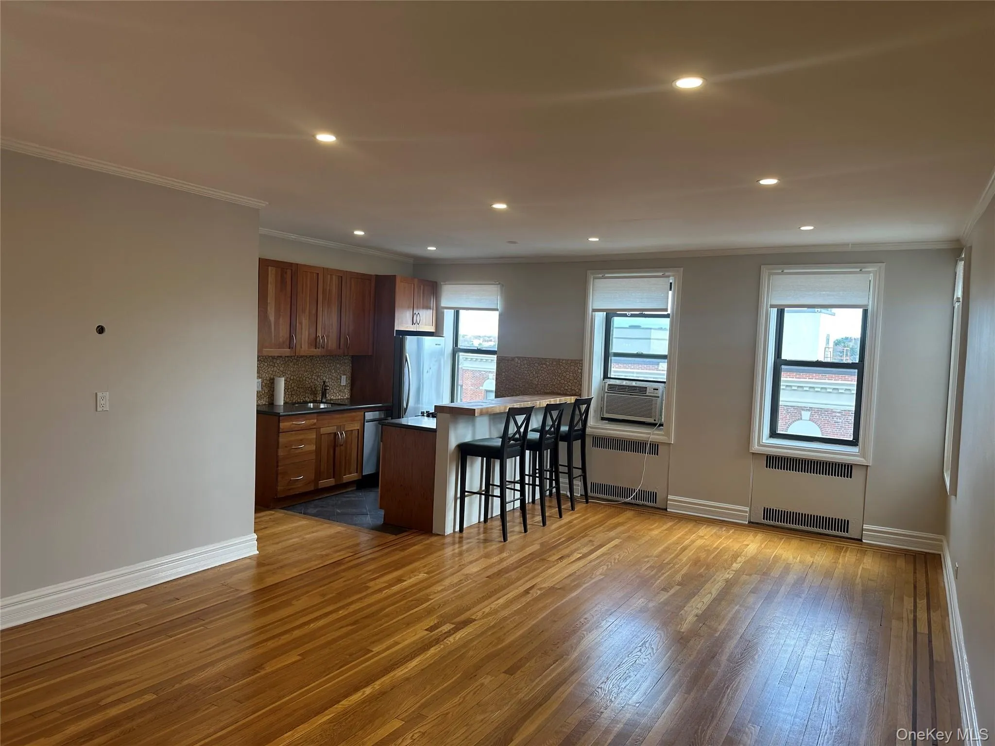 Kitchen with a breakfast bar area, stainless steel appliances, radiator, backsplash, and ornamental molding Kitchen with a breakfast bar area, stainless steel appliances, radiator, backsplash, and ornamental molding