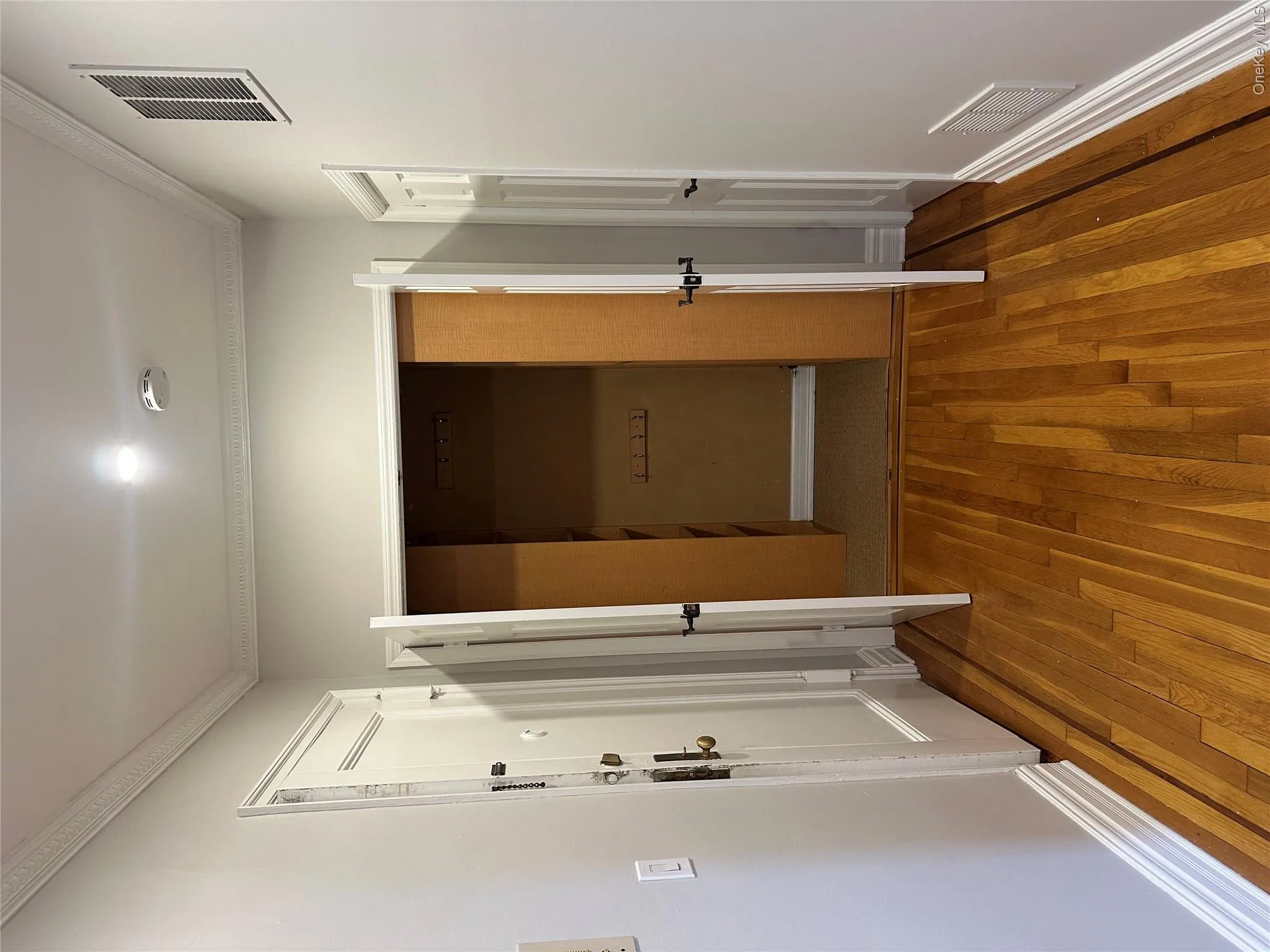 Hall featuring hardwood / wood-style floors, visible vents, and ornamental molding Hall featuring hardwood / wood-style floors, visible vents, and ornamental molding