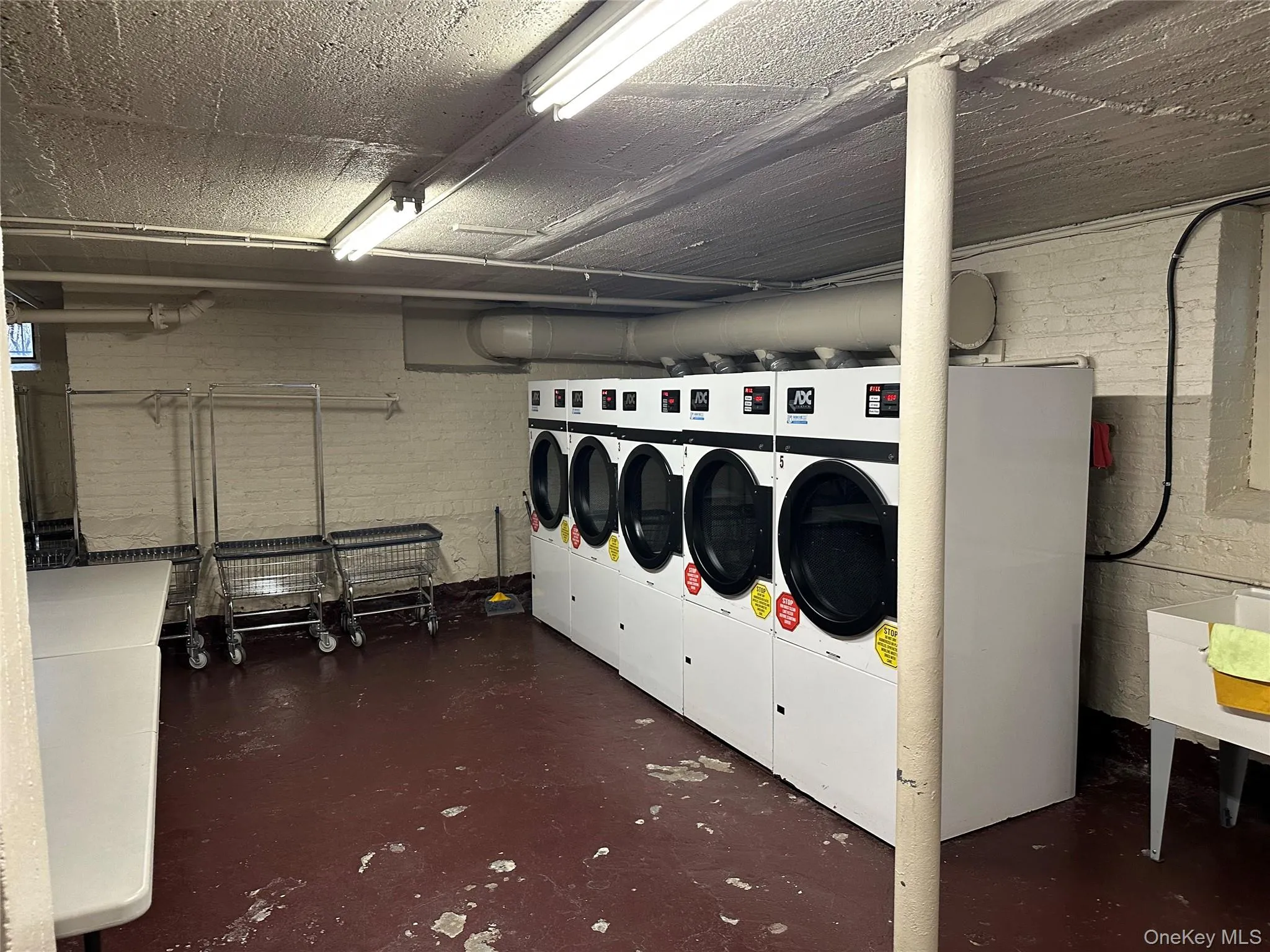 Community laundry room with washing machine and dryer and concrete block wall Community laundry room with washing machine and dryer and concrete block wall