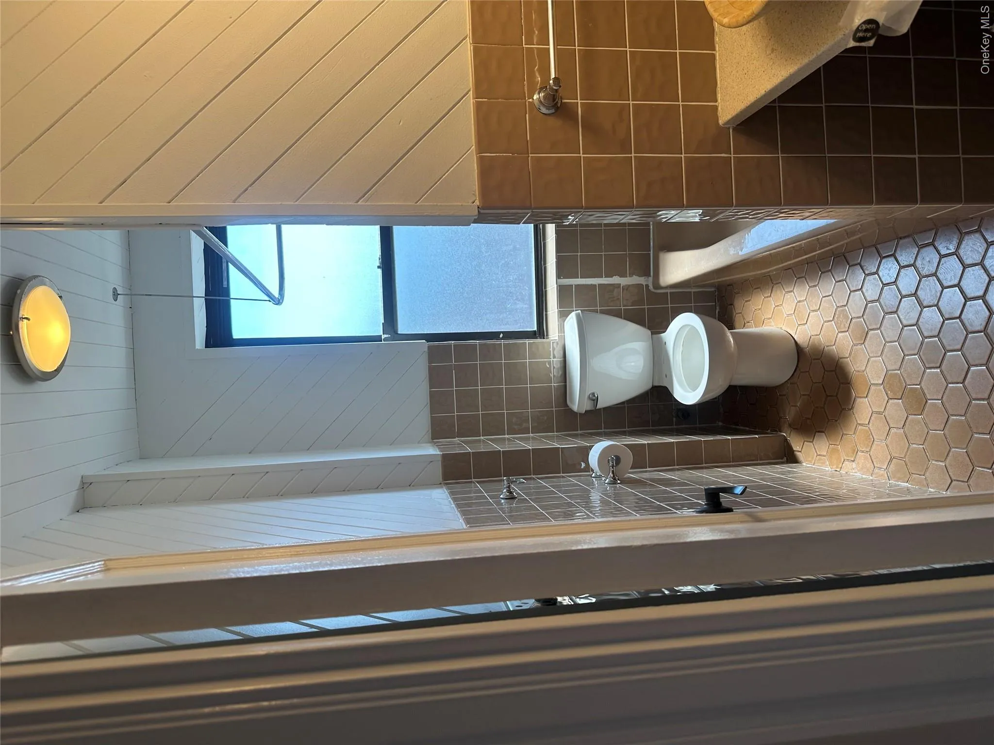 Bathroom with tile walls, toilet, a tub, and tile patterned floors Bathroom with tile walls, toilet, a tub, and tile patterned floors