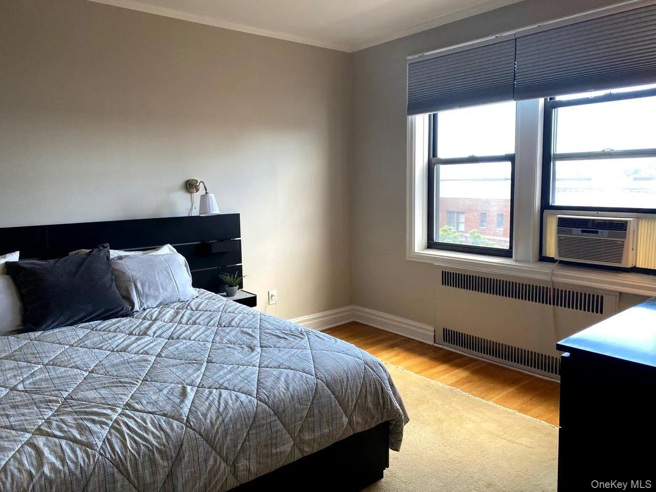 Bedroom with radiator heating unit, wood finished floors, baseboards, and crown molding Bedroom with radiator heating unit, wood finished floors, baseboards, and crown molding