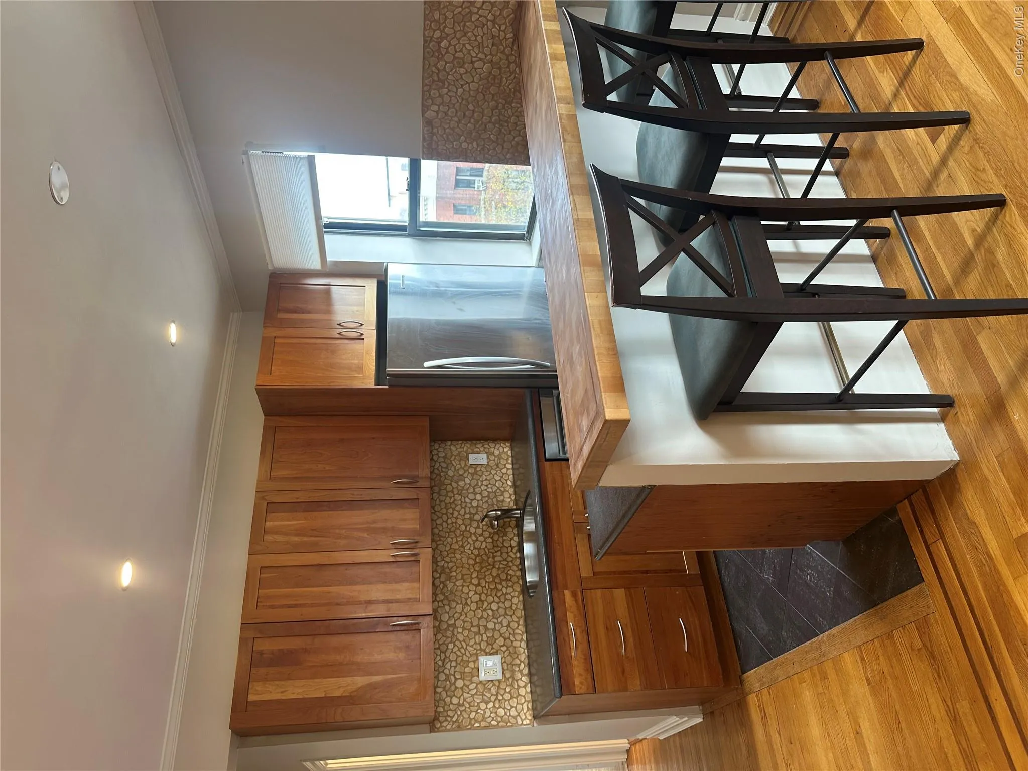 Kitchen featuring backsplash, dark countertops, a sink, freestanding refrigerator, and brown cabinetry Kitchen featuring backsplash, dark countertops, a sink, freestanding refrigerator, and brown cabinetry
