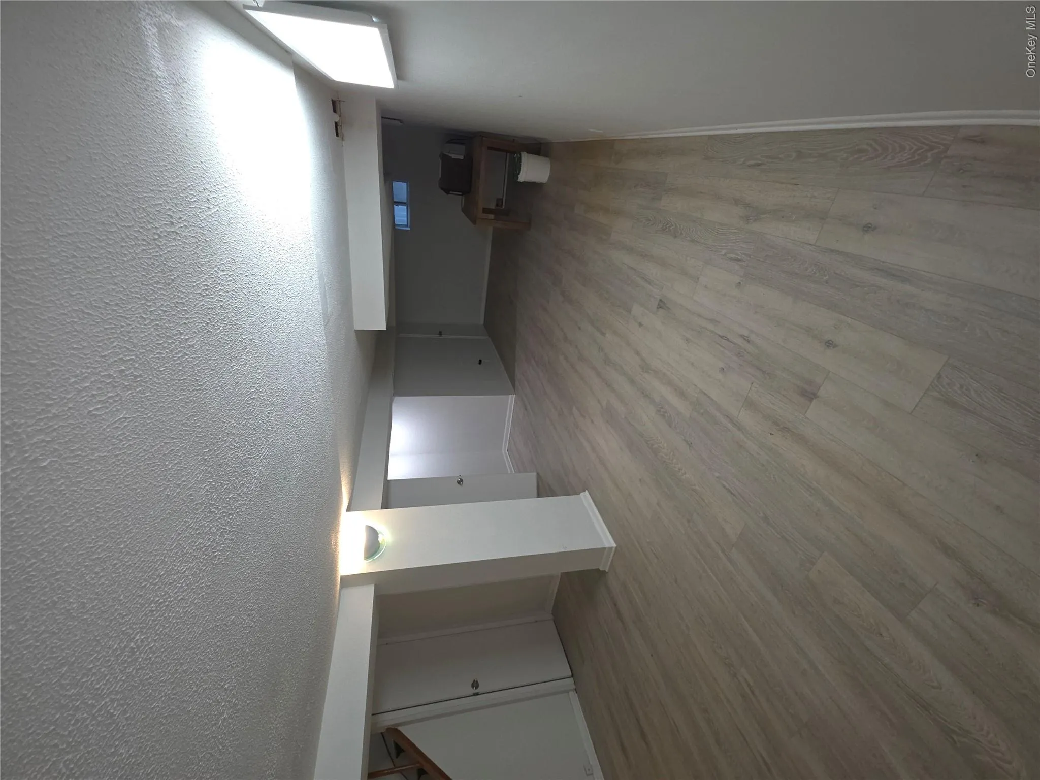 Spacious finished lower level featuring light gray wood-finish flooring, white painted walls, recessed lighting, and a partially enclosed utility space Spacious finished lower level featuring light gray wood-finish flooring, white painted walls, recessed lighting, and a partially enclosed utility space