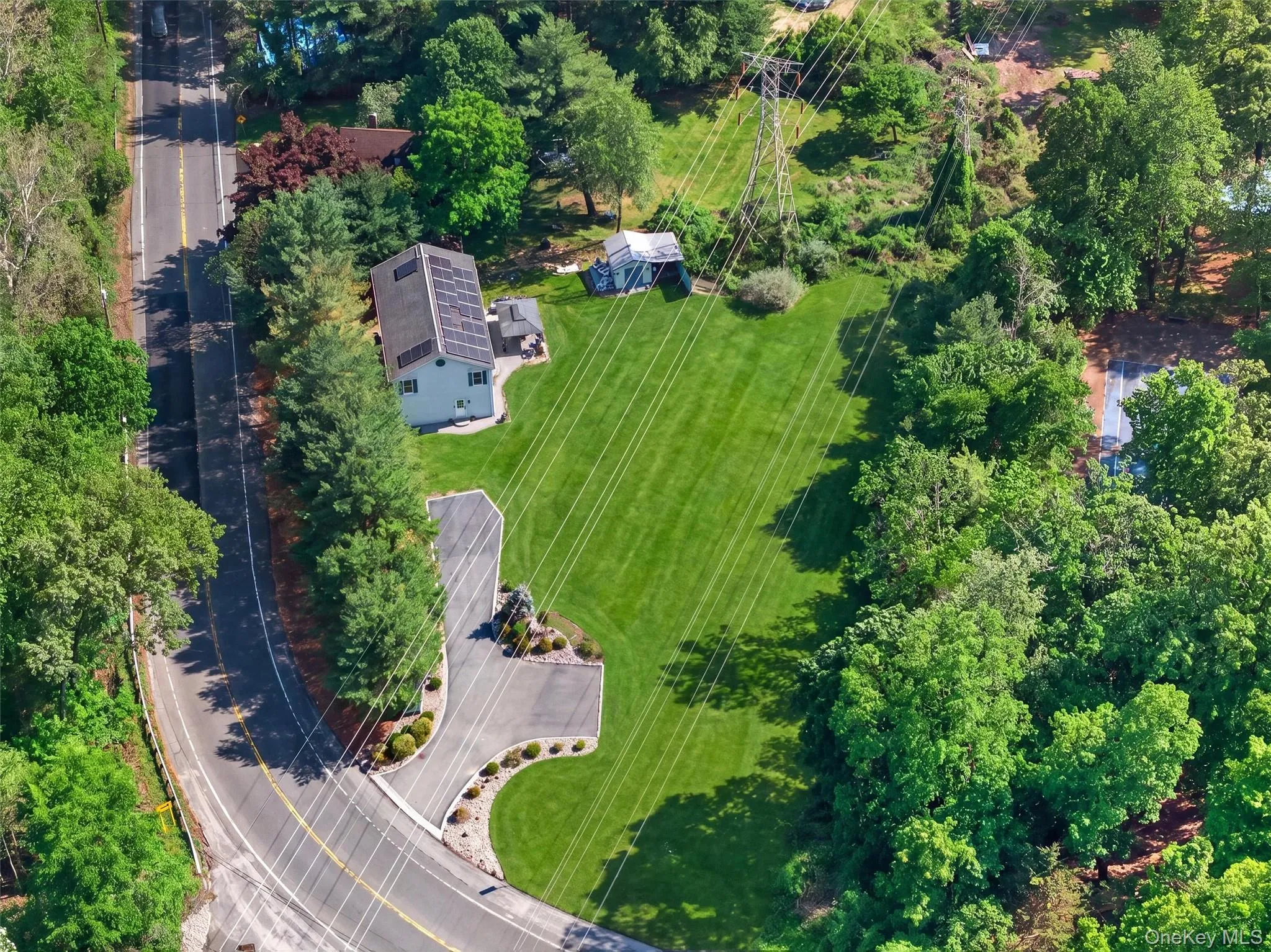 Aerial view highlighting the expansive property, long driveway, large backyard, and surrounding natural landscape. Aerial view highlighting the expansive property, long driveway, large backyard, and surrounding natural landscape.