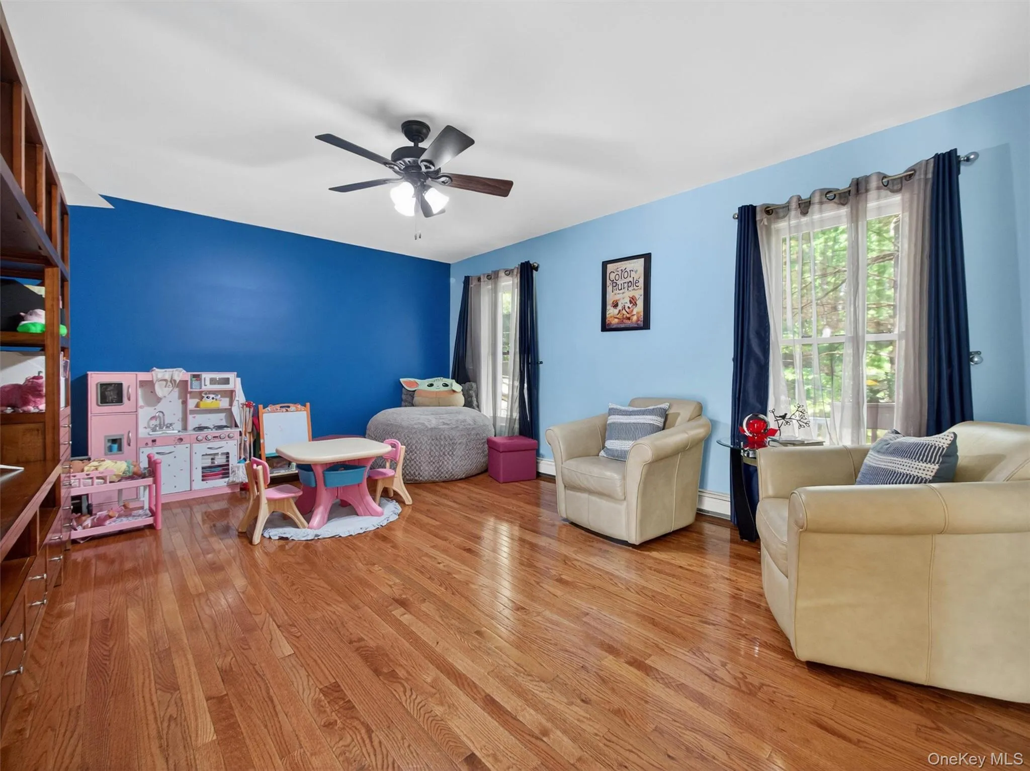 Spacious family room featuring hardwood floors, large windows, and flexible living space currently used as a play area. Spacious family room featuring hardwood floors, large windows, and flexible living space currently used as a play area.