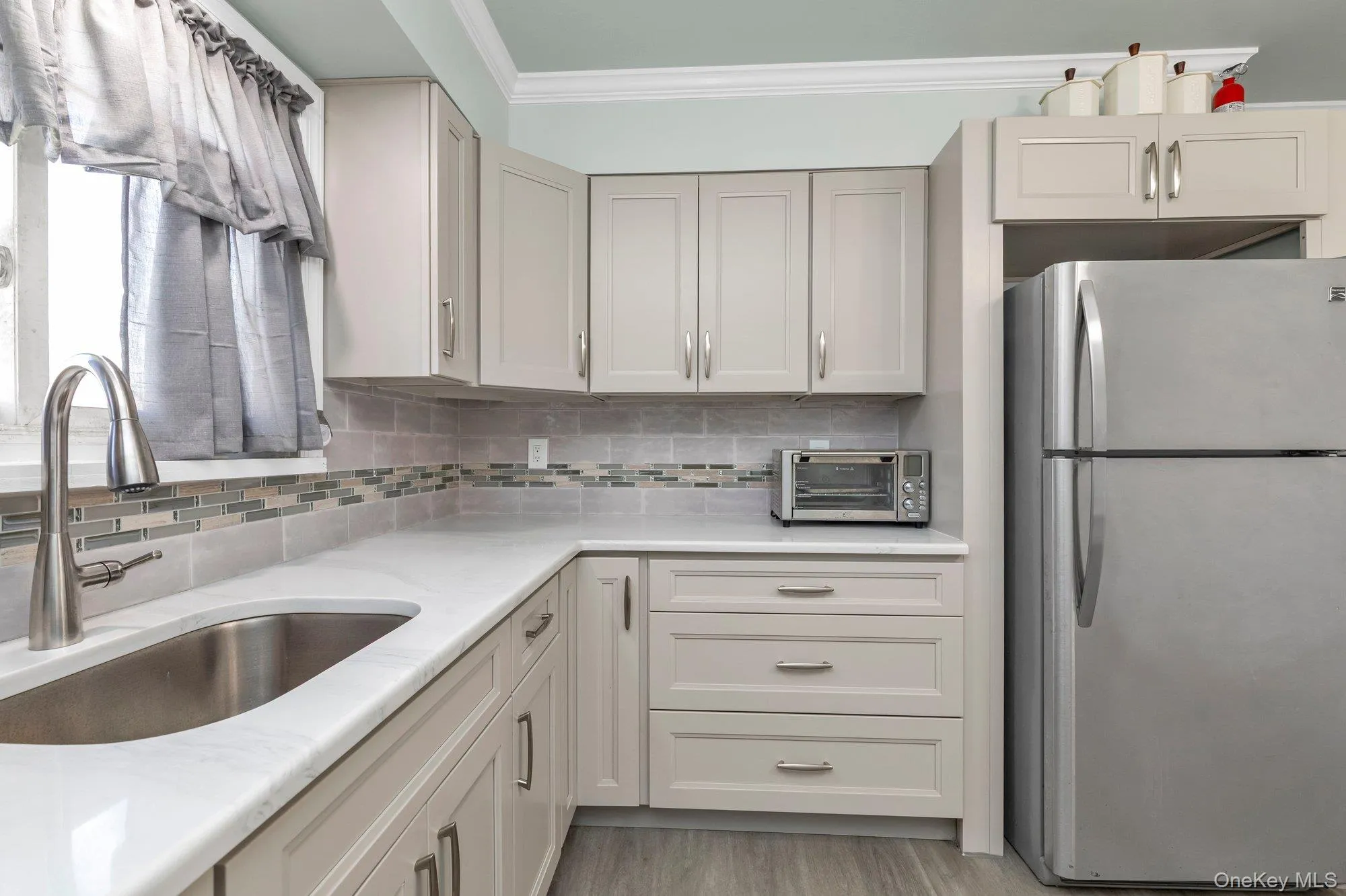 Brand new kitchen featuring light-toned cabinetry, a stainless steel sink with a high-arc faucet, and light-toned countertops Brand new kitchen featuring light-toned cabinetry, a stainless steel sink with a high-arc faucet, and light-toned countertops