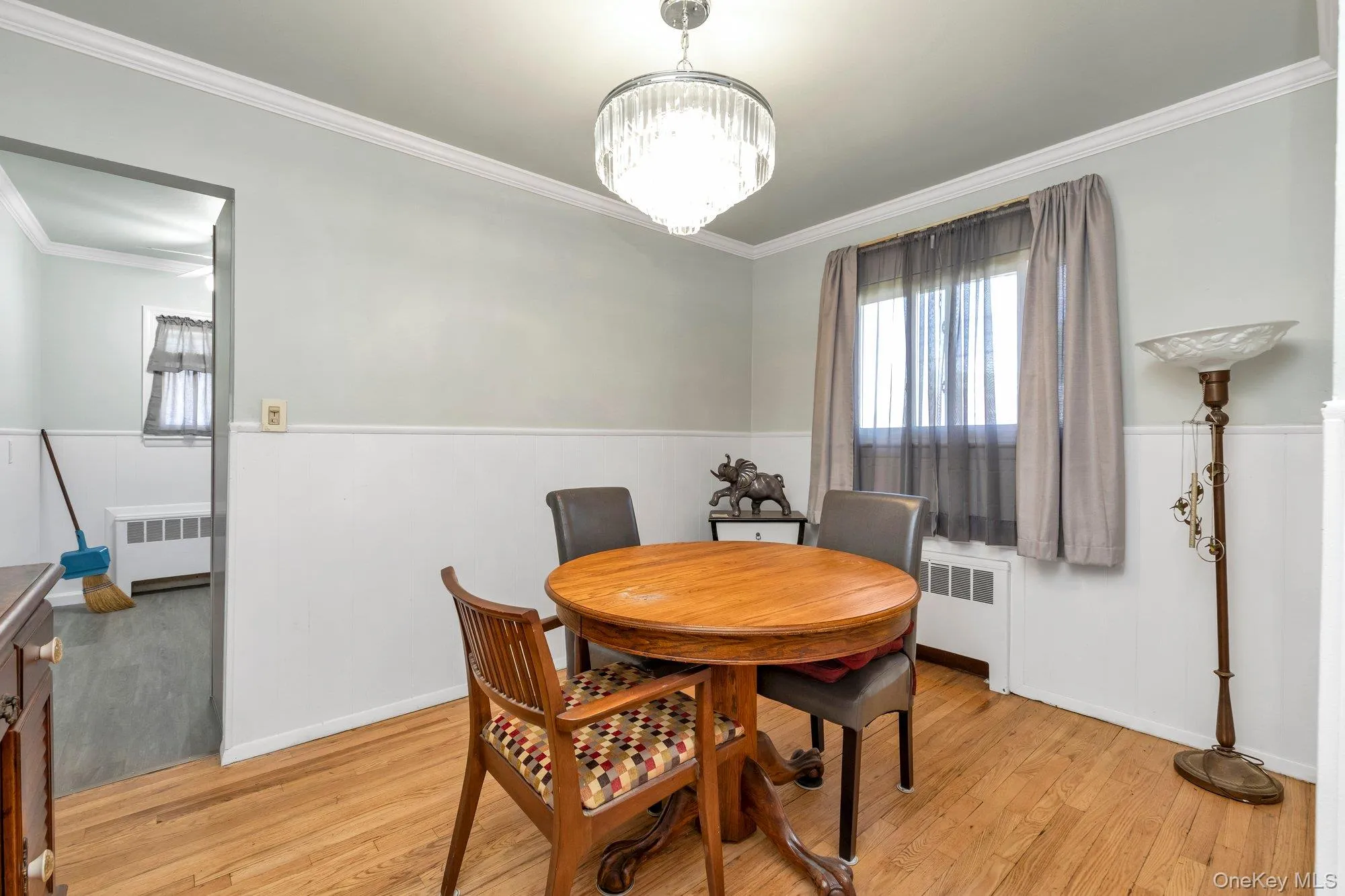 Dining space featuring wood-finish flooring, a crystal chandelier, and crown molding Dining space featuring wood-finish flooring, a crystal chandelier, and crown molding