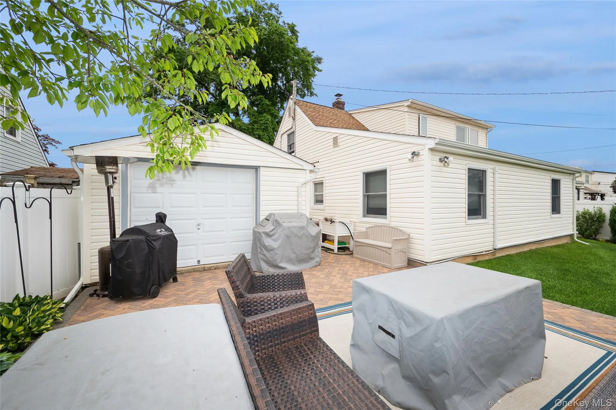 Back of garage with additional real garage door, beautiful patio overlooking manicured yard Back of garage with additional real garage door, beautiful patio overlooking manicured yard