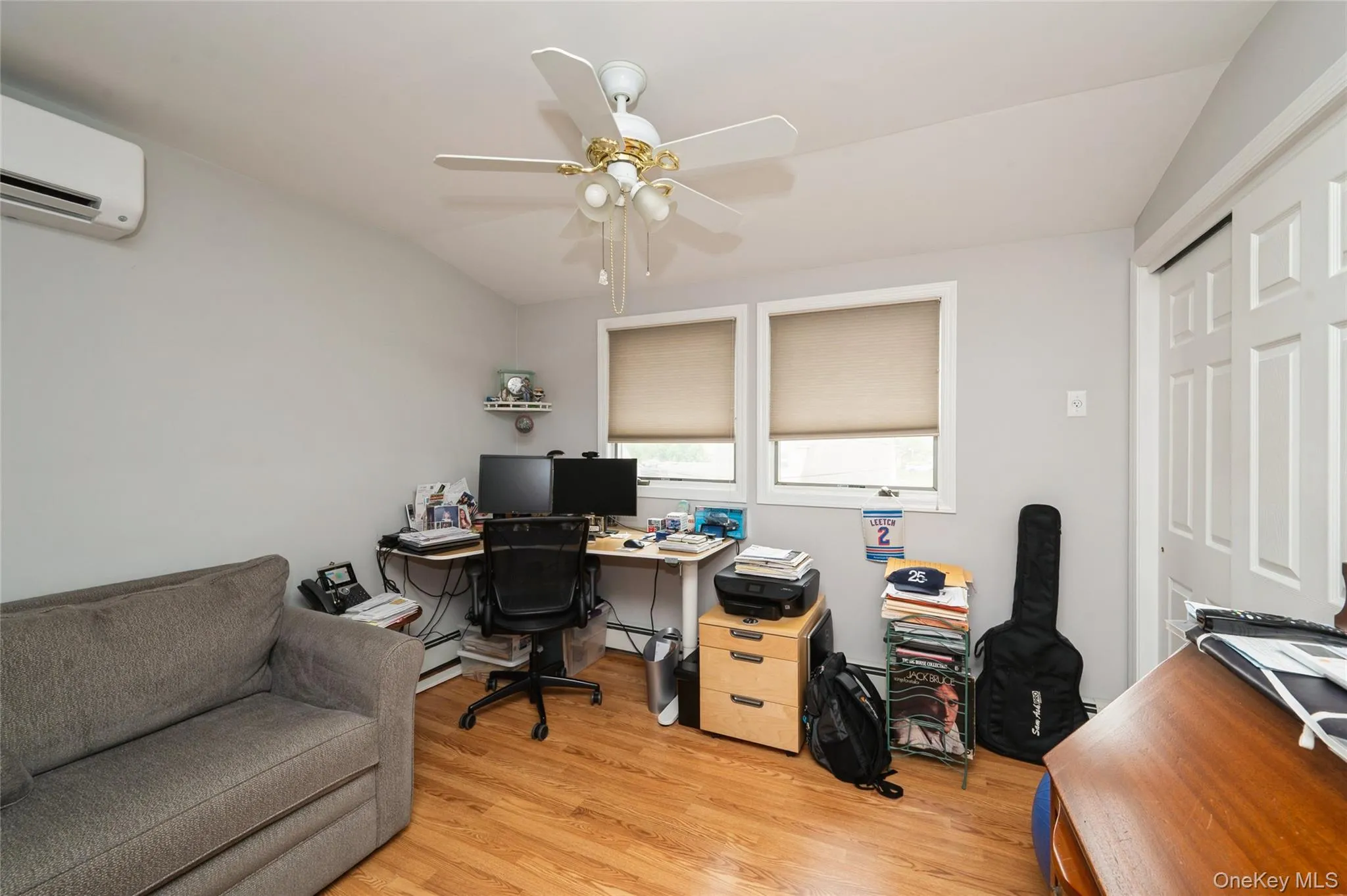 Room with wood-finish flooring, two windows, and a ceiling fan with integrated lighting Room with wood-finish flooring, two windows, and a ceiling fan with integrated lighting