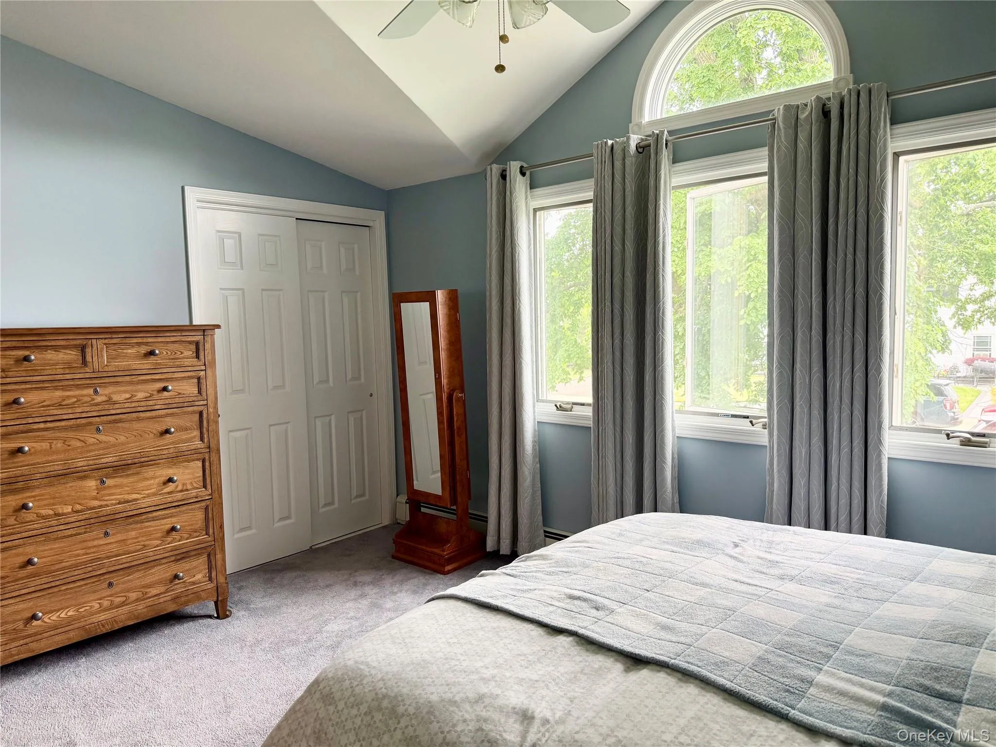 Primary Bedroom with vaulted ceiling, arched transom window, three rectangular windows, and a ceiling fan Primary Bedroom with vaulted ceiling, arched transom window, three rectangular windows, and a ceiling fan