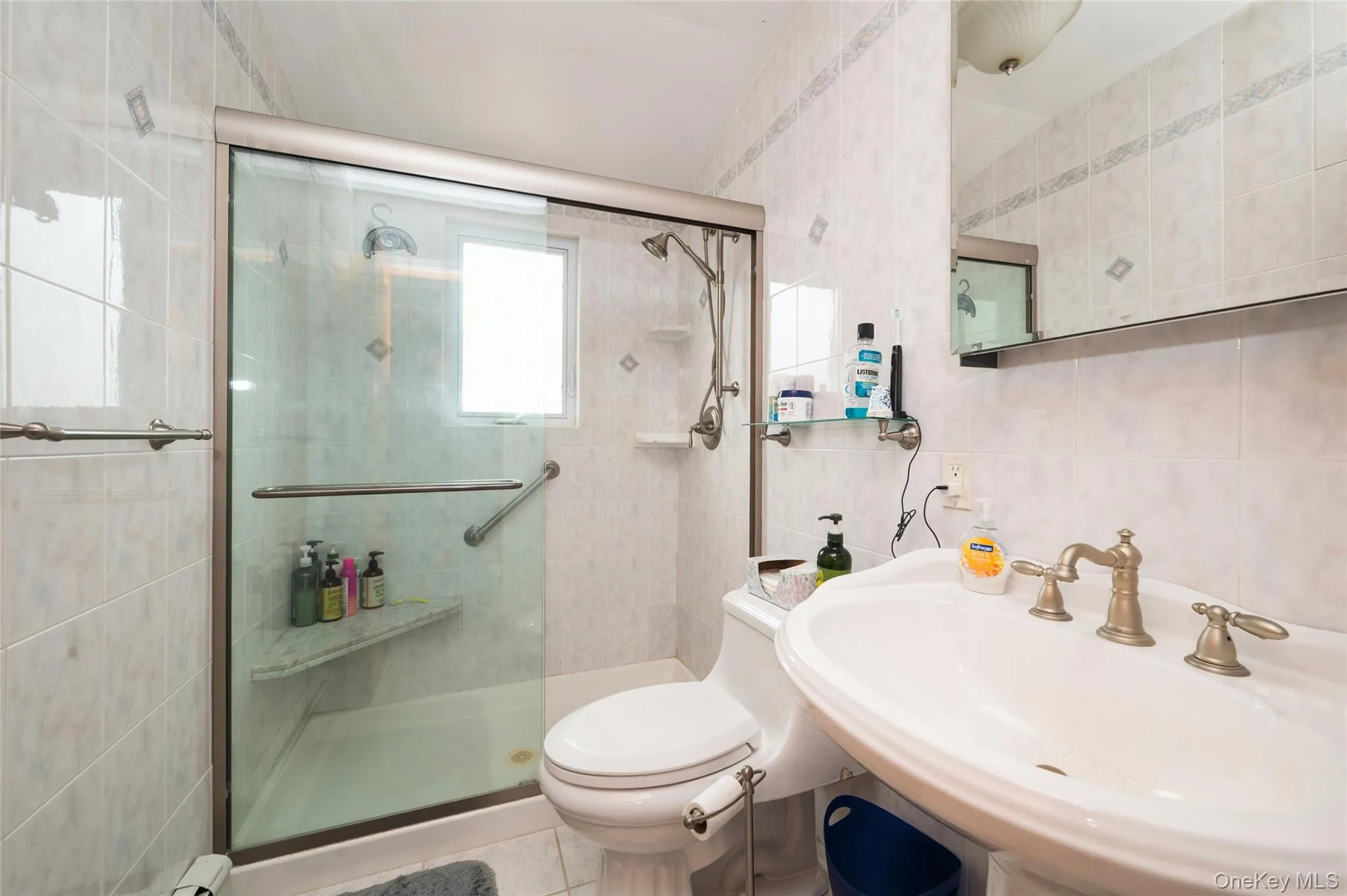 Bathroom featuring a shower with a sliding glass door, a built-in shower bench, and a window Bathroom featuring a shower with a sliding glass door, a built-in shower bench, and a window