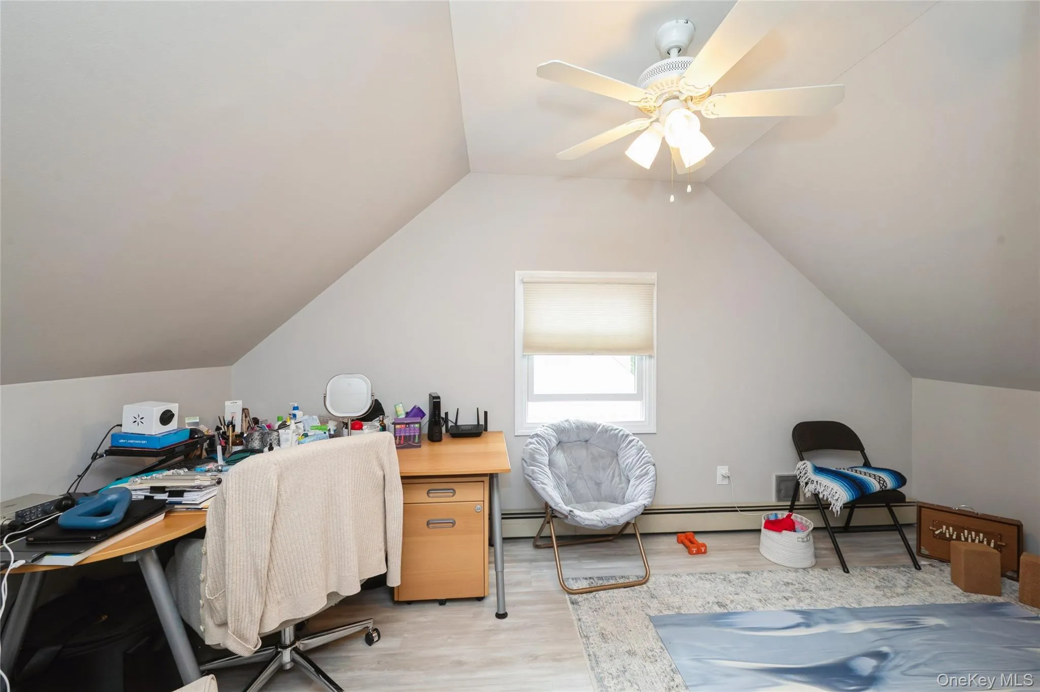 Bonus space or extra bedroom featuring sloped ceilings, a single window with a roller shade, wood-finish flooring, a ceiling fan with integrated lighting, and light gray wall paint Bonus space or extra bedroom featuring sloped ceilings, a single window with a roller shade, wood-finish flooring, a ceiling fan with integrated lighting, and light gray wall paint