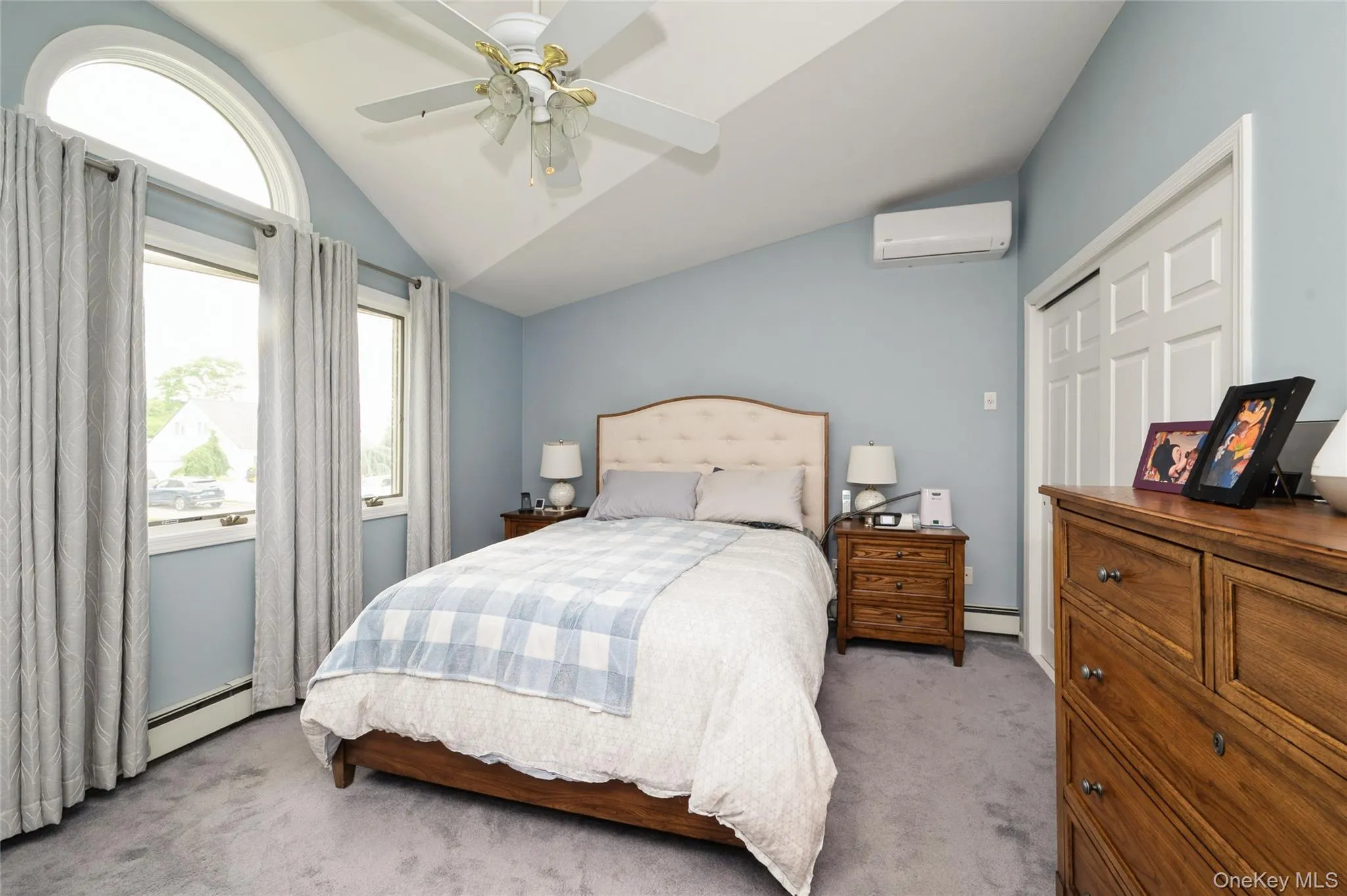 Primary bedroom with vaulted ceiling featuring an arched window and ceiling fan Primary bedroom with vaulted ceiling featuring an arched window and ceiling fan
