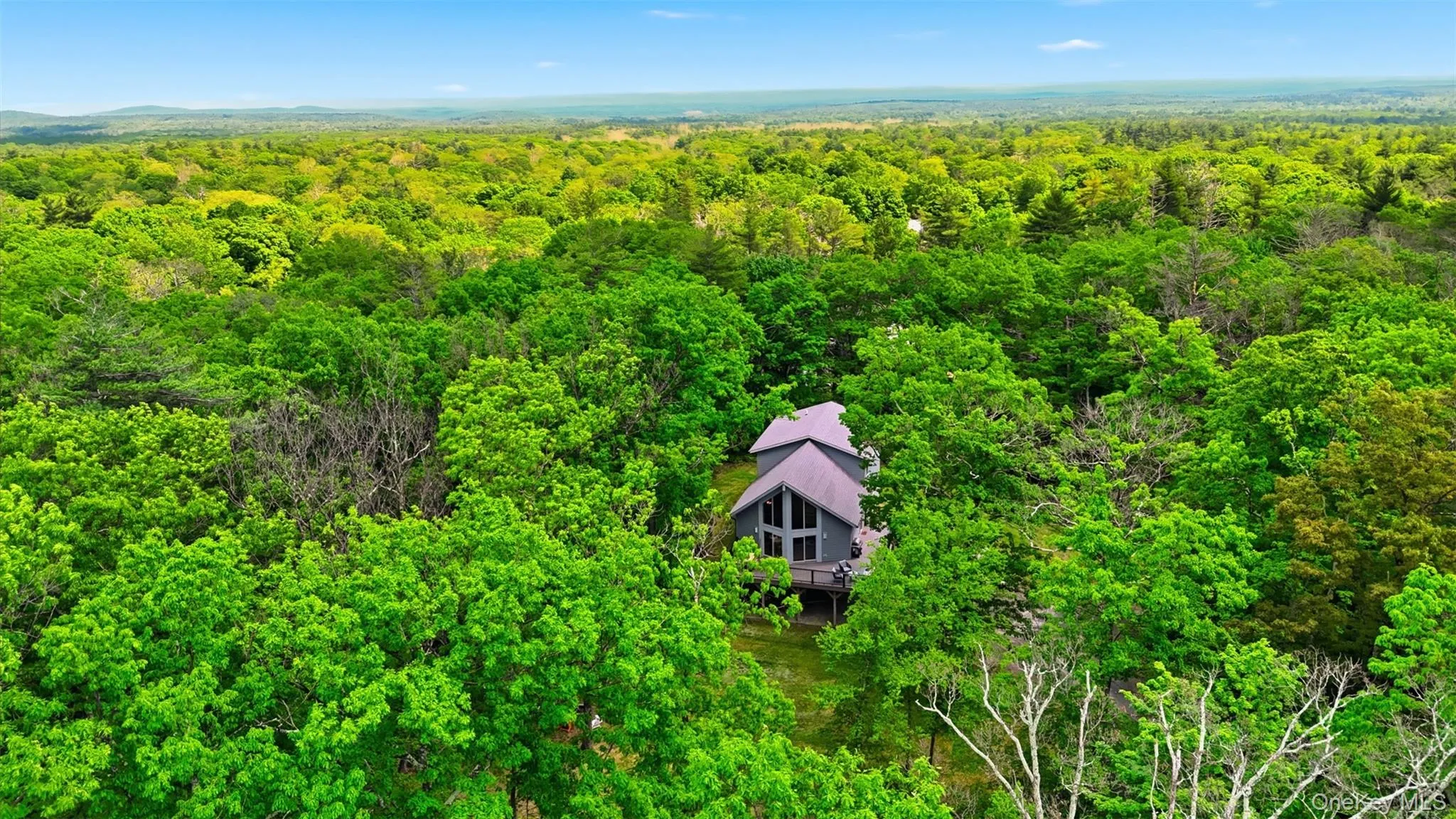 Contemporary residence nestled amidst trees, featuring a multi-level exterior, an expansive window wall, a prominent A-frame roofline, and an elevated deck Contemporary residence nestled amidst trees, featuring a multi-level exterior, an expansive window wall, a prominent A-frame roofline, and an elevated deck