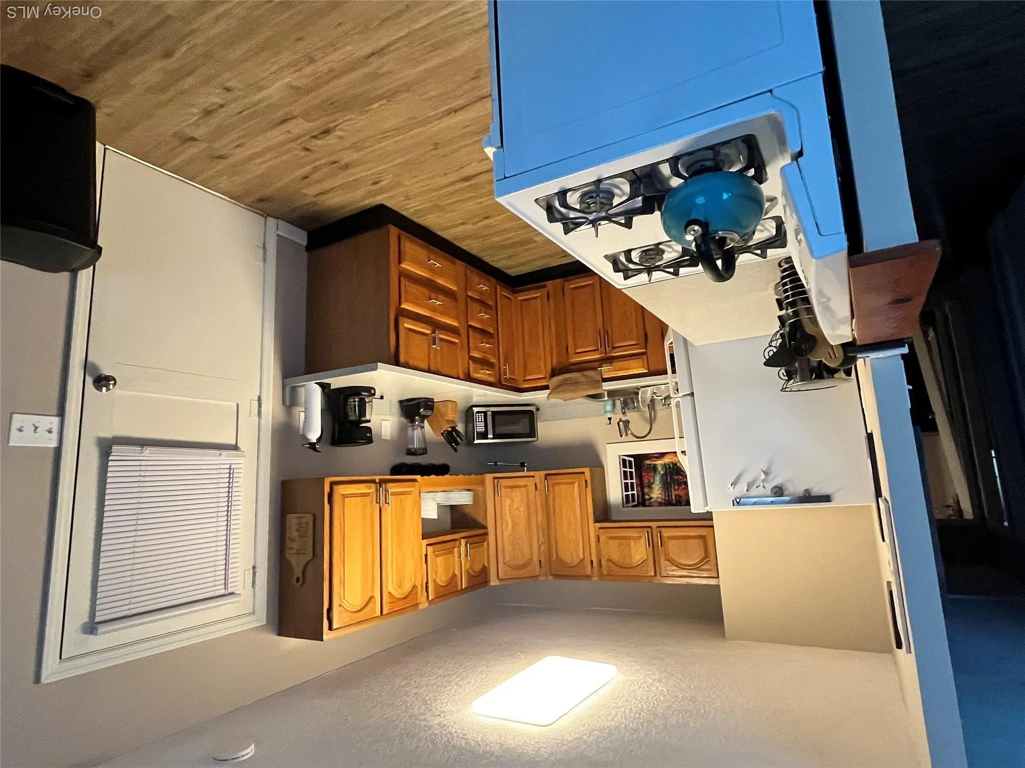 Kitchen featuring wood-finish flooring, natural wood cabinetry, a built-in sink, and light-toned countertops Kitchen featuring wood-finish flooring, natural wood cabinetry, a built-in sink, and light-toned countertops