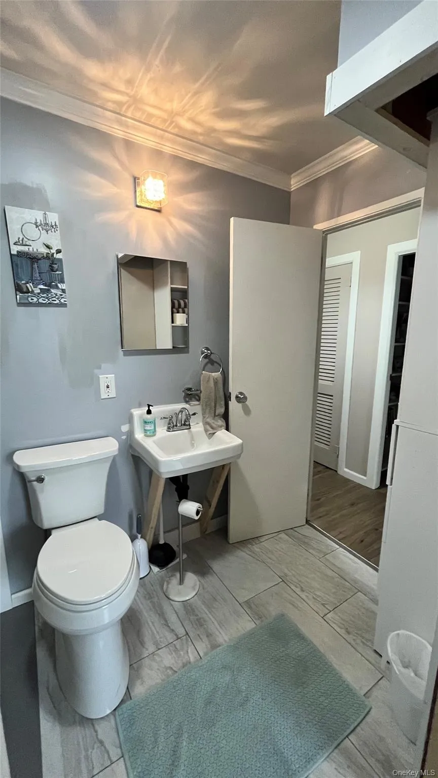 Bathroom featuring a pedestal sink with a chrome faucet, white toilet, and tile flooring Bathroom featuring a pedestal sink with a chrome faucet, white toilet, and tile flooring